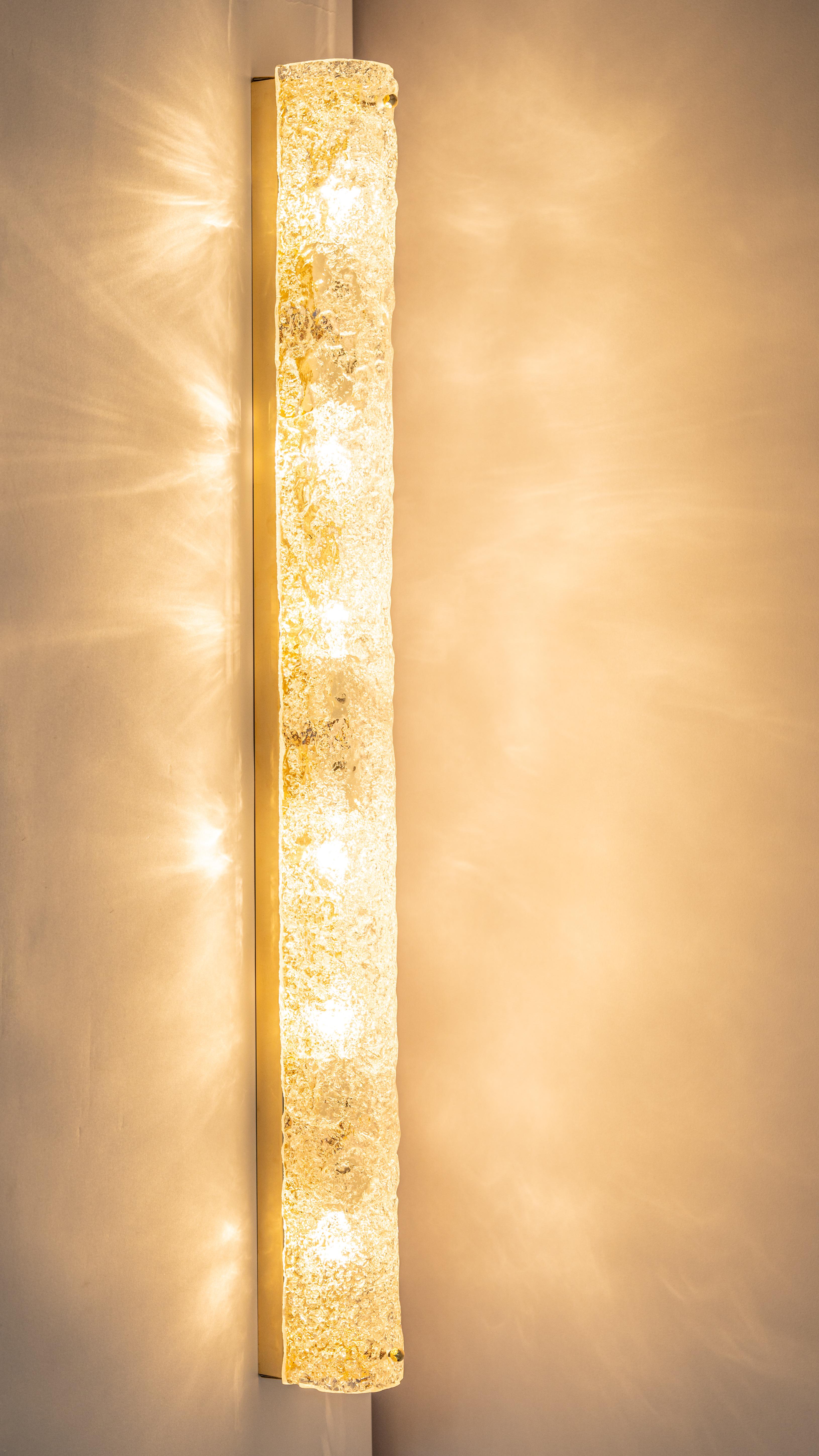 Pair of Extra-large handcrafted Murano glass on brass base sconces by Hillebrand, Germany, circa the 1960s.

It consists of textured quality clear crystal tubular shade simulating ice on a Brass frame.
The design allows this light to be placed