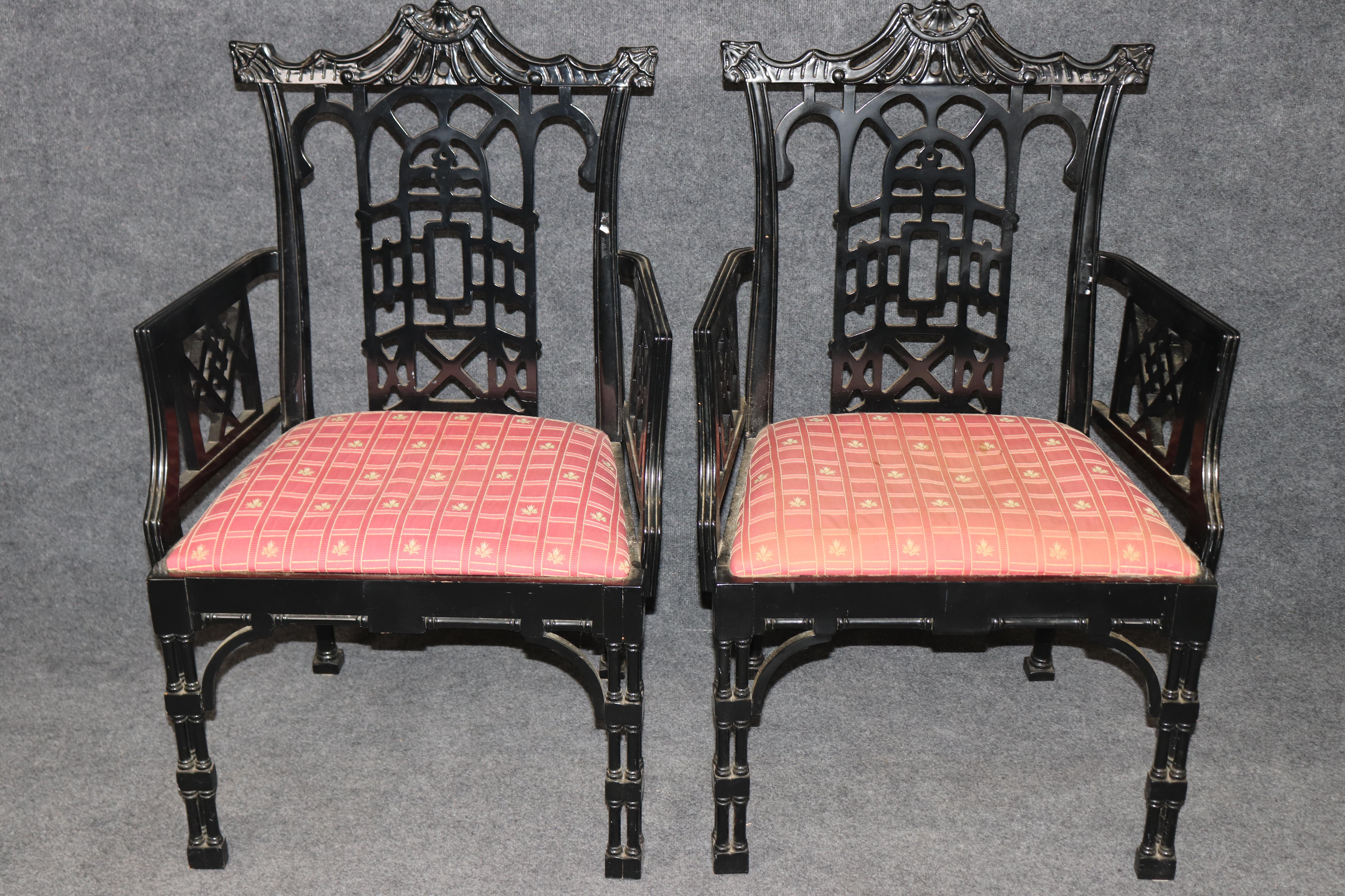 This striking pair of ebonized Chinese Chippendale style armchairs embodies the bold elegance and refined craftsmanship associated with 18th-century English design. With their intricately carved lattice backs, stylized fretwork arms, and faux bamboo
