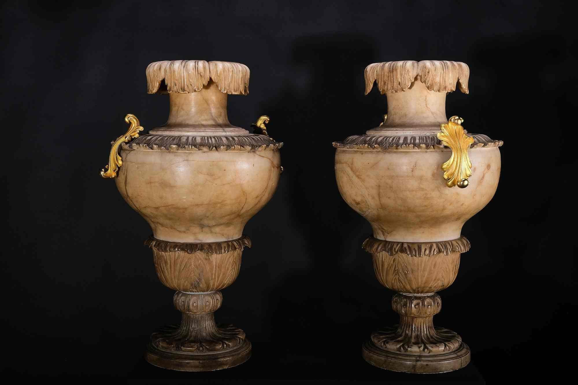 The vases have a baluster shape and are richly decorated with foliage and acanthus. The foot is multiple and decorated, the shoulder has a band of peripheral foliage with mounted and fire-gilded handles. The collar ends with a collar overflowing