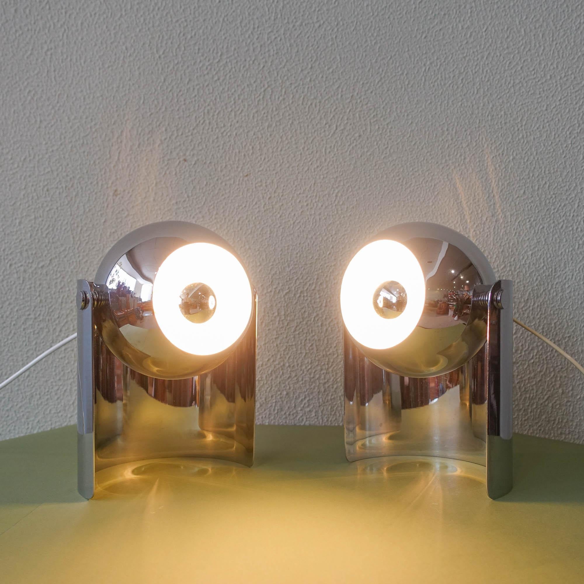 This pair of Eyeball table lamps was designed and produced by Reggiani, in Italy, during the 1970's. The chrome spotlight ball is set on a curved chromed base and it can be directed in any desired direction. In original and good vintage condition.