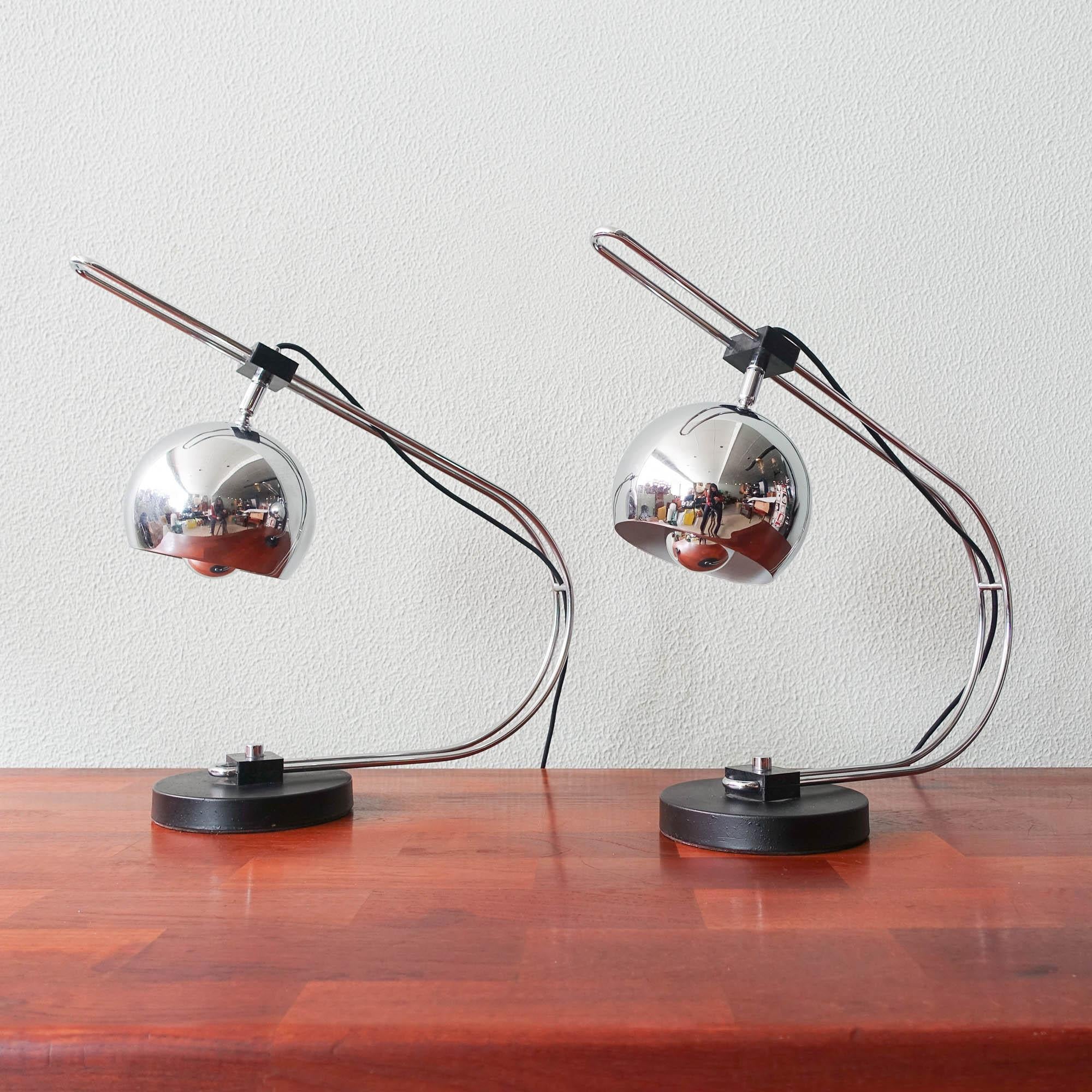 This pair of Eyeball table lamps was designed and produced by Reggiani, in Italy, during the 1970's. The chrome spotlight slides on a curved chromed stand permitting to adjust the height according to the needs. It can also be directed in any desired