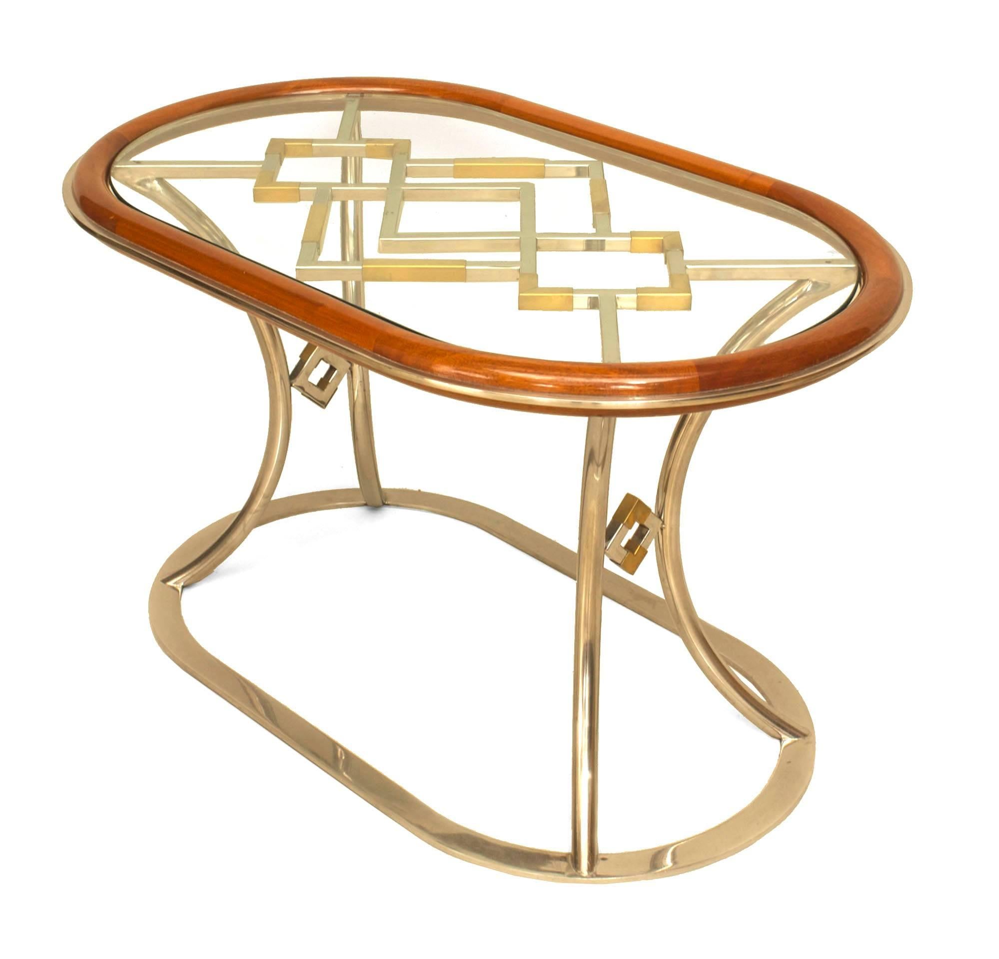 Pair of French Post-War Design (1970s) oval coffee tables with a mahogany rim holding a glass top over an open brass design resting on chrome plated base. (designed by Alain Delon for Maison Jansen) (PRICED AS Pair)
