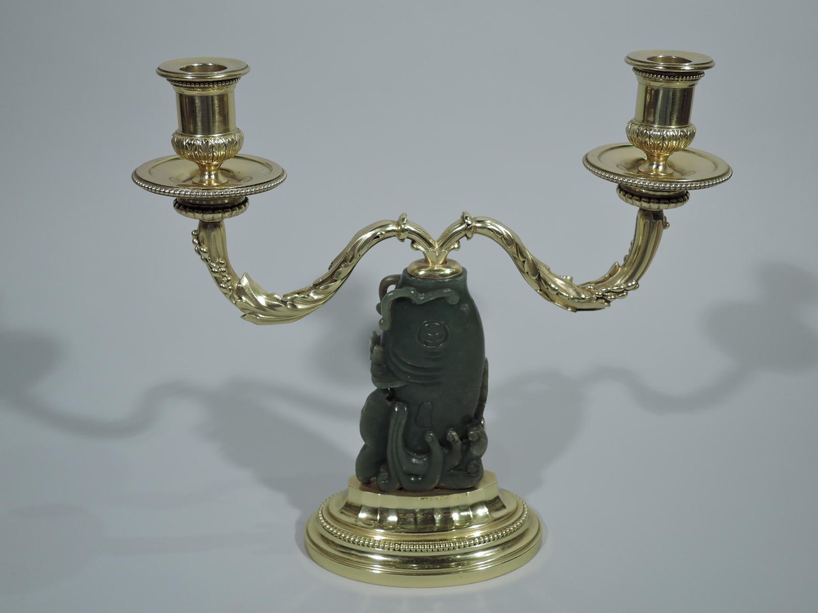 Pair of gilt 950 silver 2-light candelabra with carved jade shaft. Made by Cartier in France, circa 1930. Each: Carp shaft in carved jade mounted to stepped and beaded oval base. Set in gaping fish mouth are two leaf-wrapped arms each terminating in