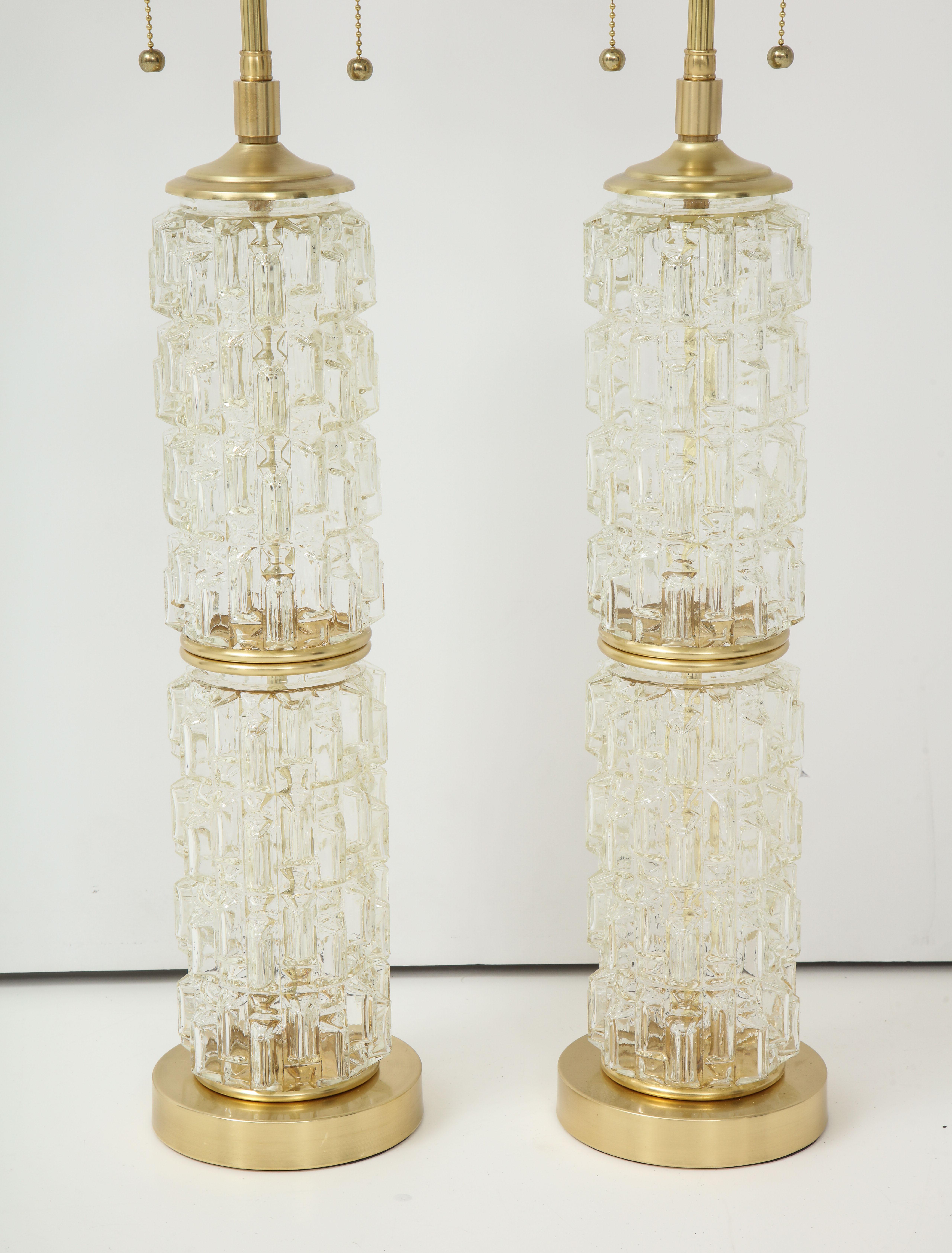 Pair of 1970s faceted cut glass lamps with polished brass hardware.
The lamps have been newly rewired with polished brass double clusters.