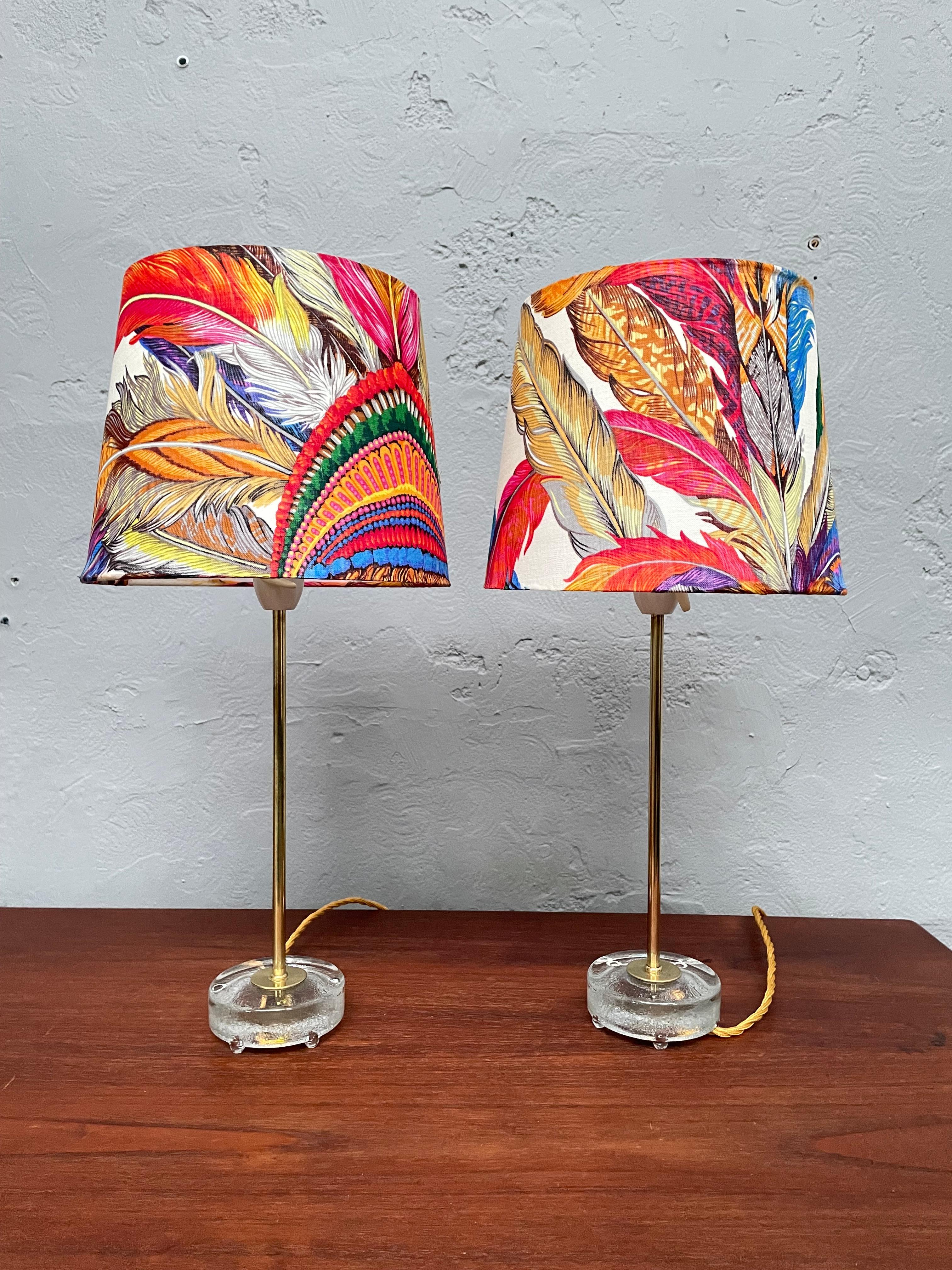 A pair of beautiful midcentury table lamps by Falkenberg lighting factory of Sweden. 
These gorgeous lamps are standing on a round glass base and with a brass stem. 
The lamps still have their original white plastic  bulb holders with an on/off