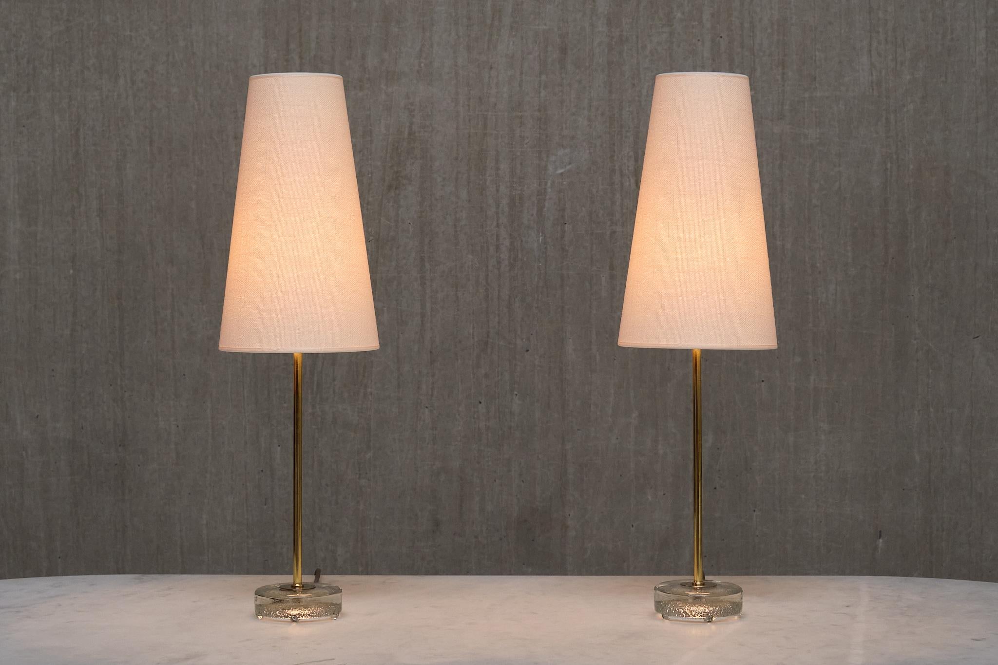 This elegant pair of table lamps was produced by Falkenbergs Belysning in Sweden in the 1960s. The lamps are signed with the manufacturers initials FLB on the bottom of the base.  

The design is composed of a slightly raised, circular foot in