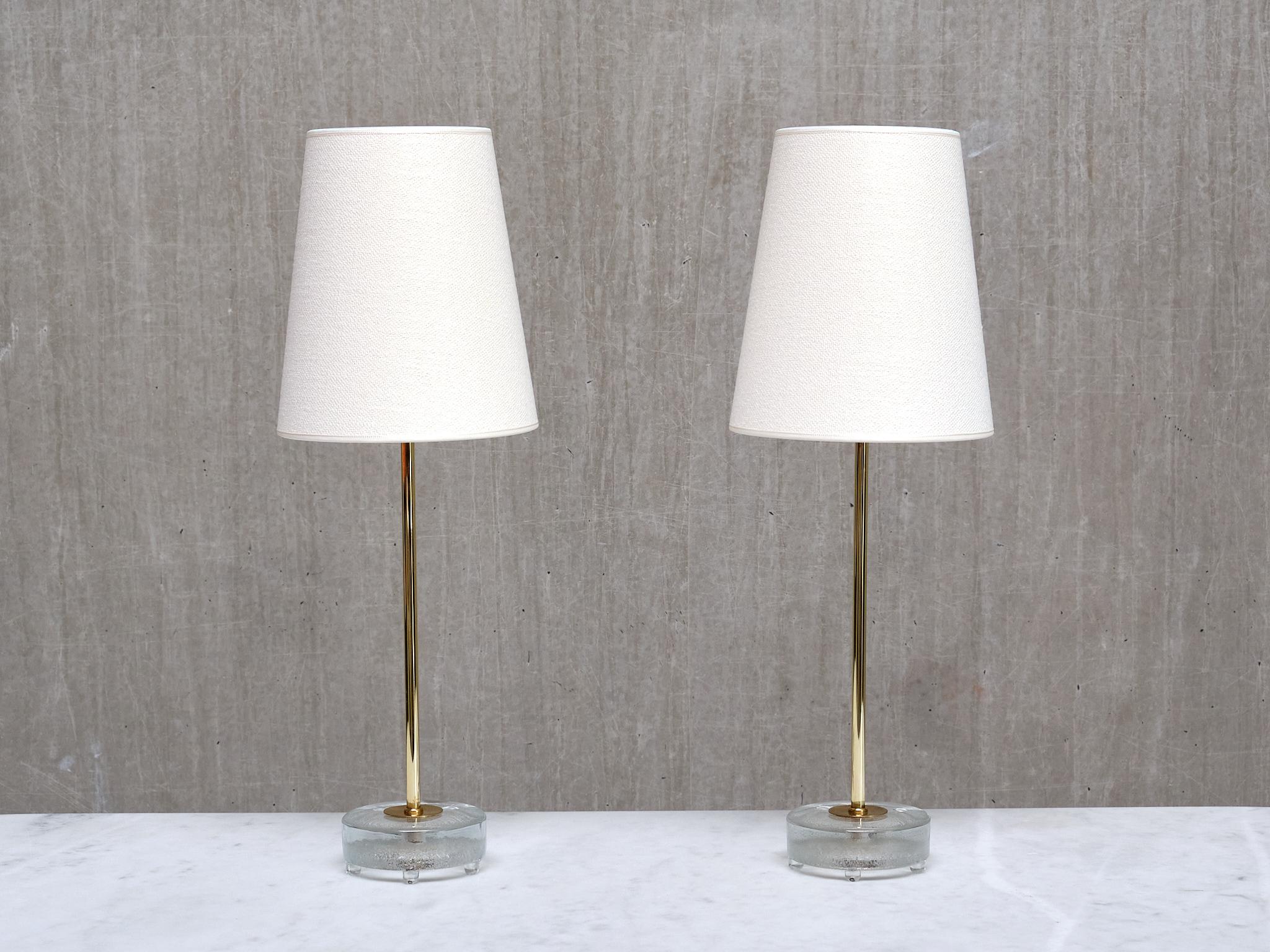 Cette élégante paire de lampes de table a été produite par Falkenbergs Belysning en Suède dans les années 1960. Les lampes sont signées avec les initiales du fabricant FLB sur la base du socle.   

Le design se compose d'un pied circulaire