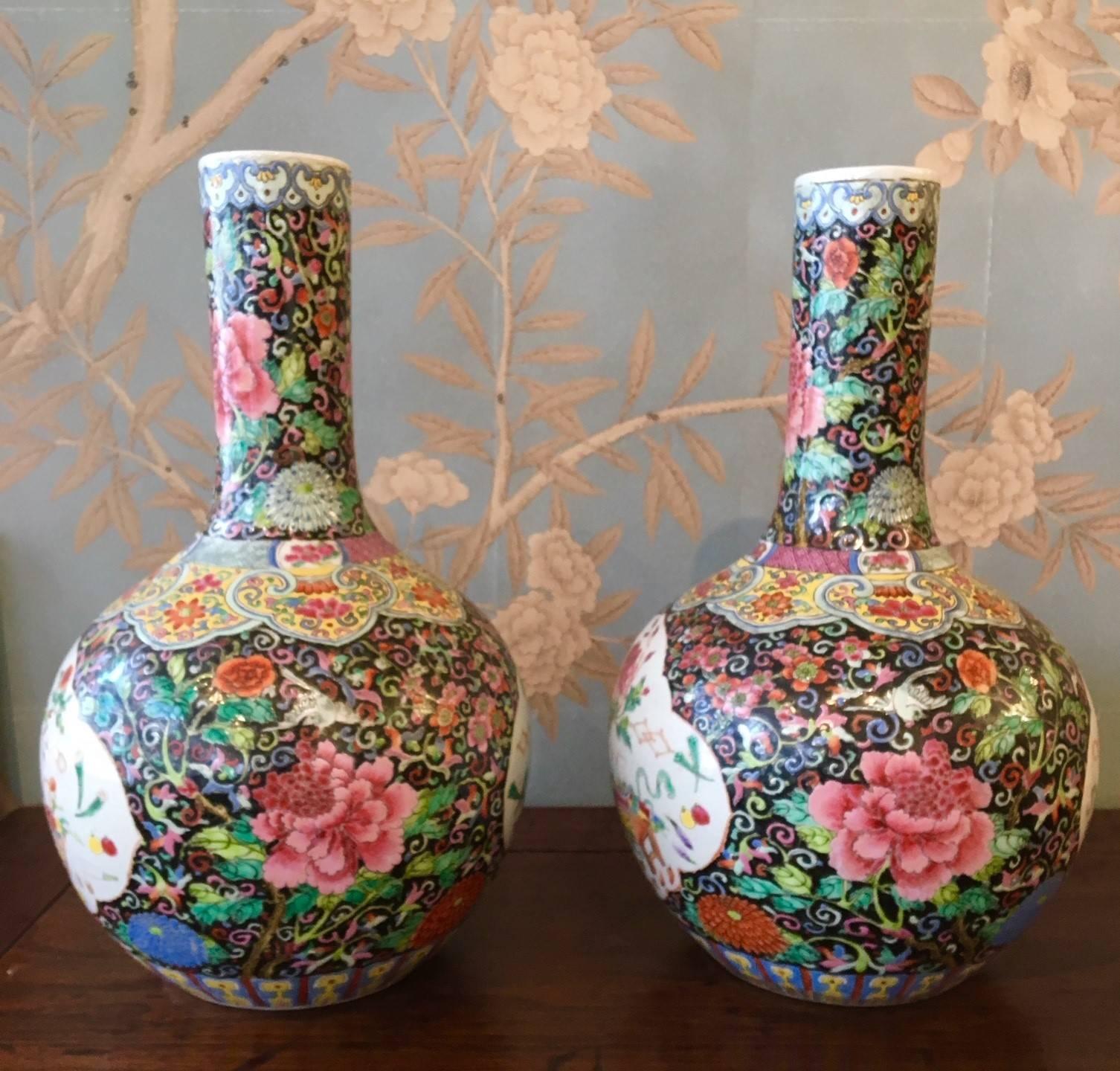 A pair of early 20th century famille noire vases with reserves of floral design.