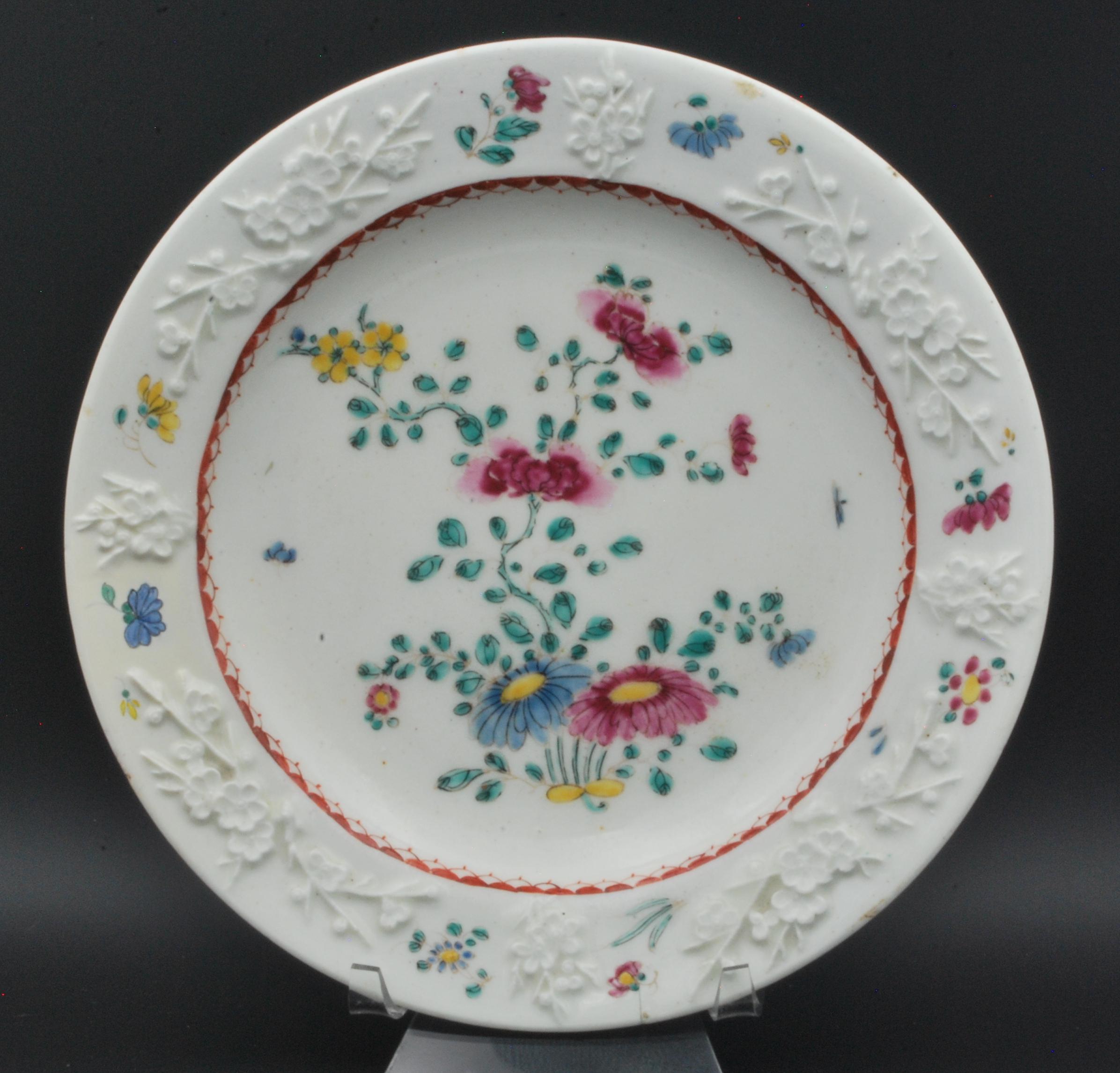 A fine pair of plates with raised decoration of prunus, and painted with a famille rose pattern.