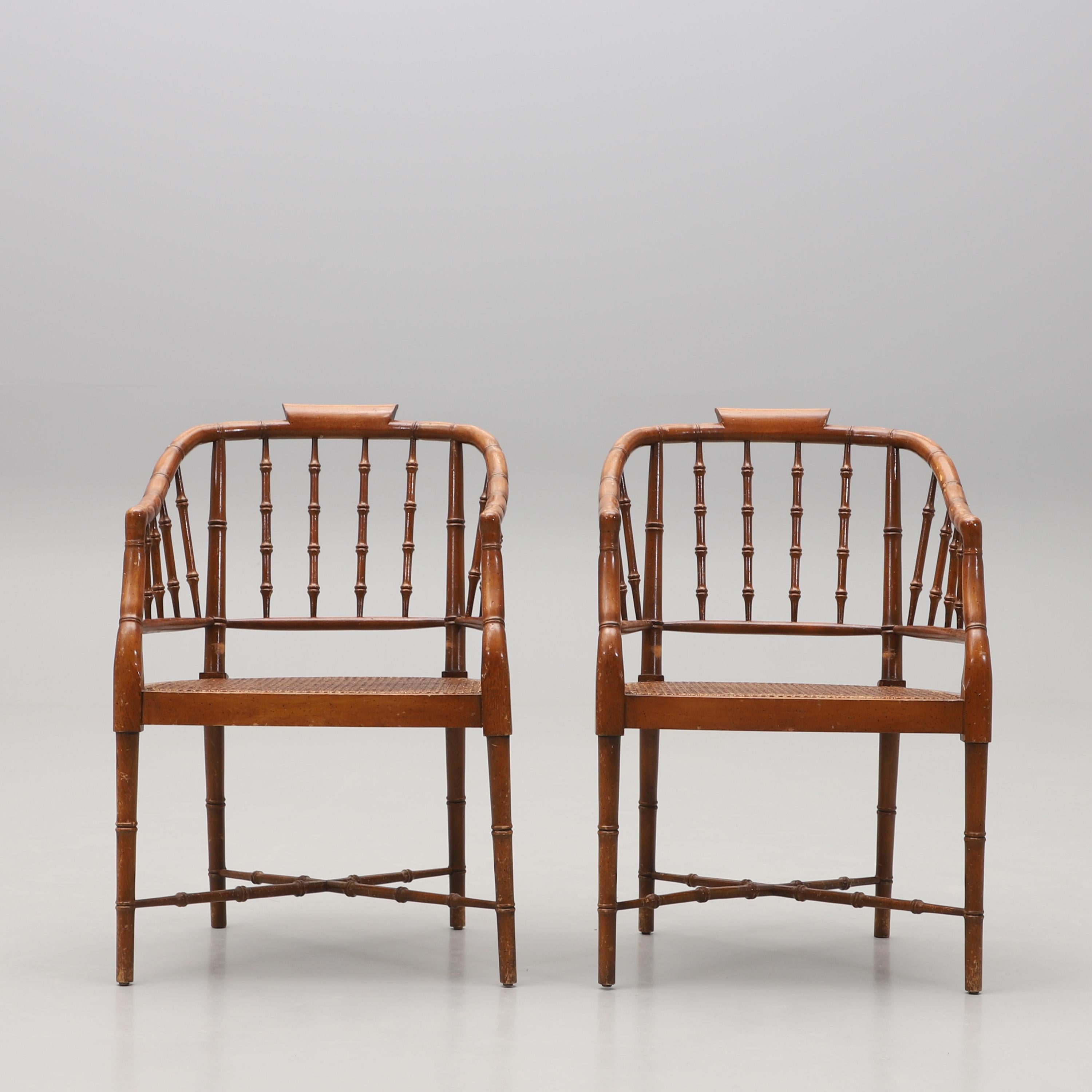 Pair faux-bamboo chairs, by Baker continuous arm surmounted with curved tablet over bamboo spindles, with cane seat and corresponding legs and stretchers. 