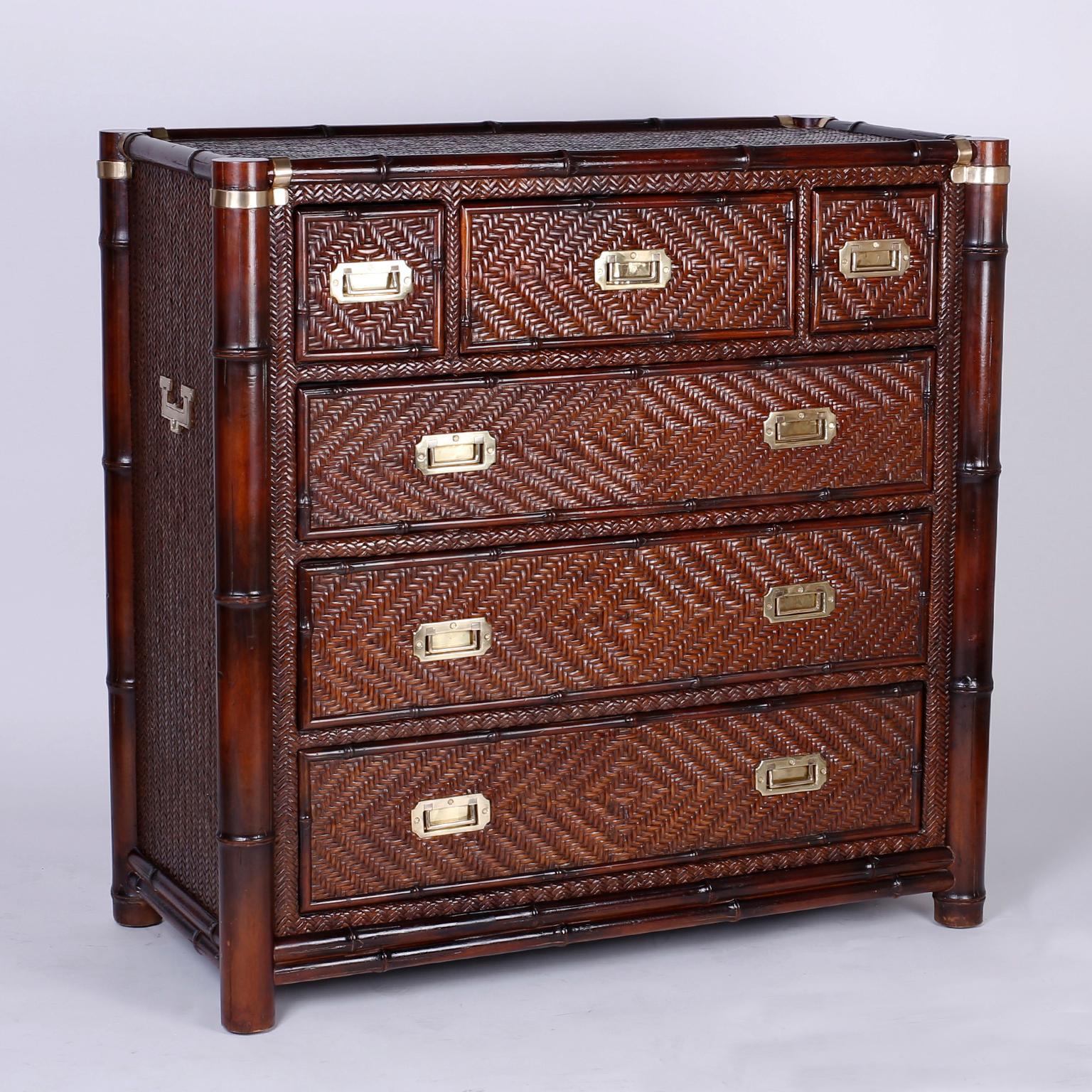 Handsome pair of British Colonial style chests of drawers with carved wood, faux bamboo frames over cases wrapped in herring bone rattan, while the inset brass hardware gives them a Campaign reference. The backs are finished and the chests are