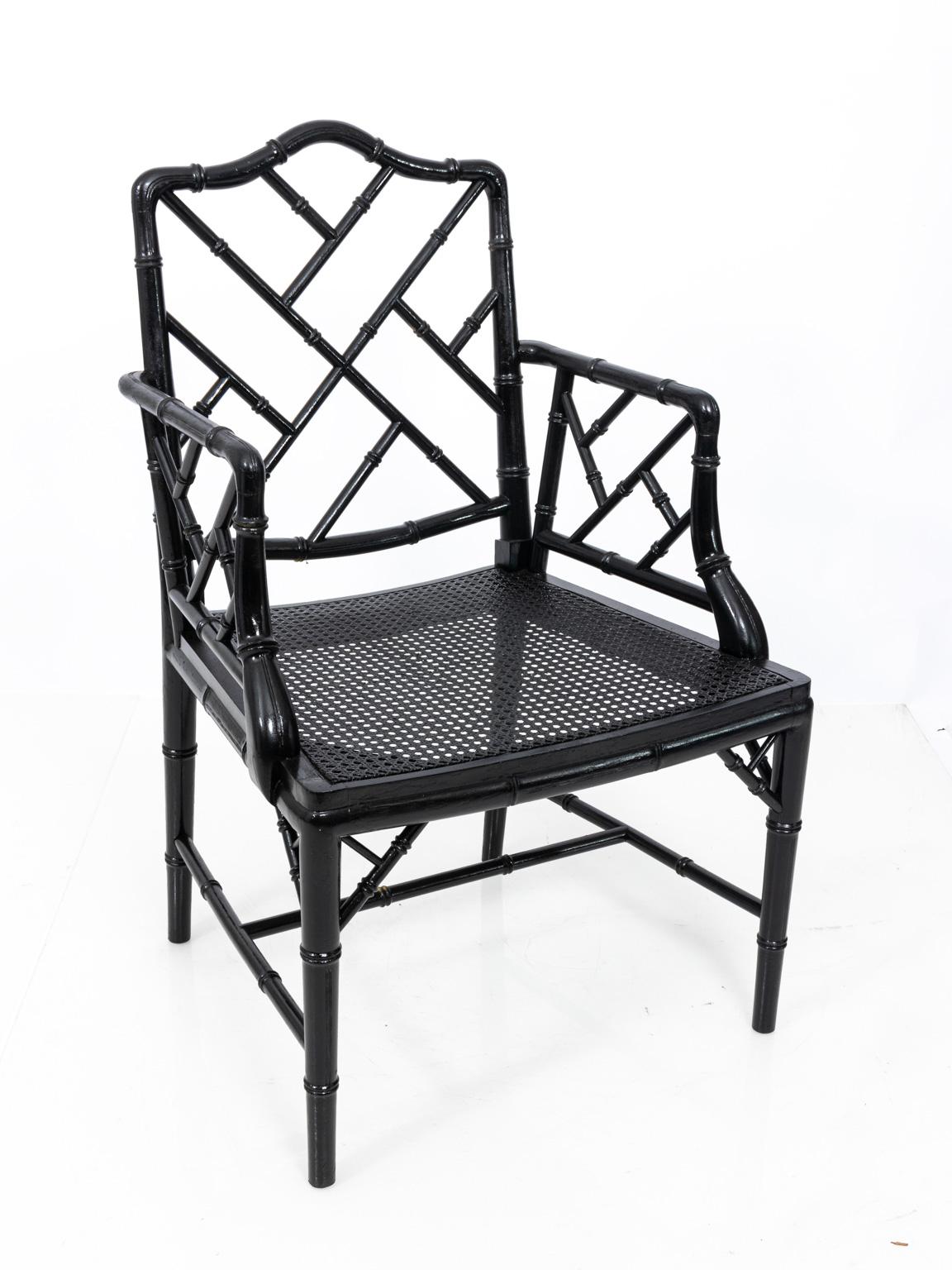 Pair of faux bamboo armchairs in a black lacquered finish with woven cane seat, circa 1960s. Please note of wear consistent with age including paint loss and minor scratches.