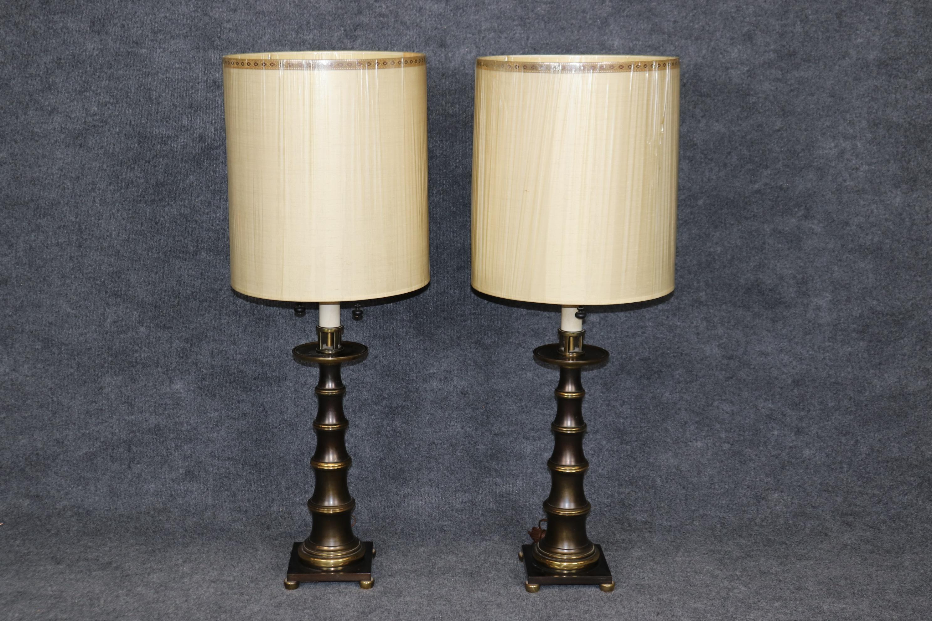 This is a fantastic pair of faux bamboo brass table lamps by the famous Stiffel who made some wonderful lamps in the USA. The lamps are in good condition and have their original stove-pipe lamp shades. Measures 16.5 wide x 44.75 tall with lampshades