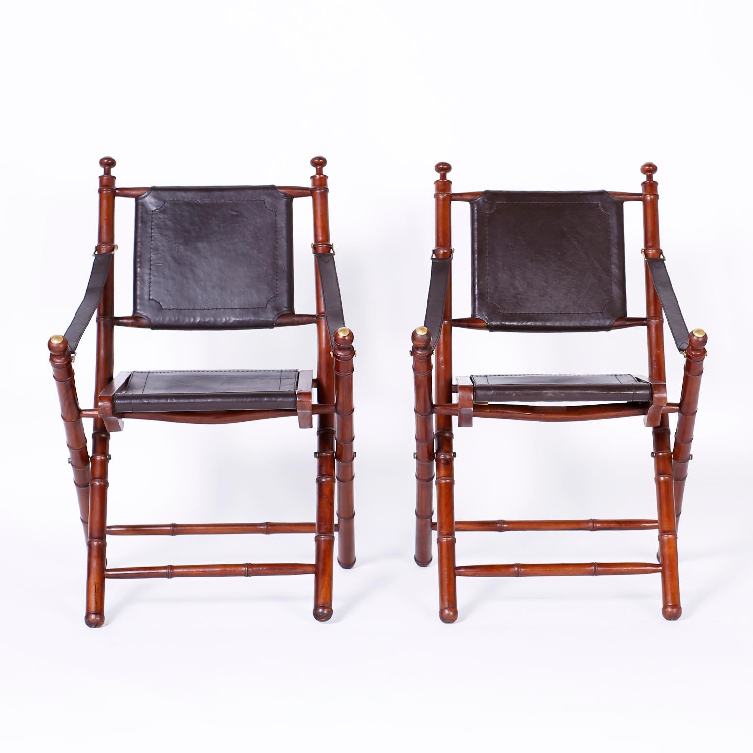 Pair of midcentury folding faux bamboo chairs expertly crafted in mahogany with brass hardware and soft leather backs, seats, and strap arms.