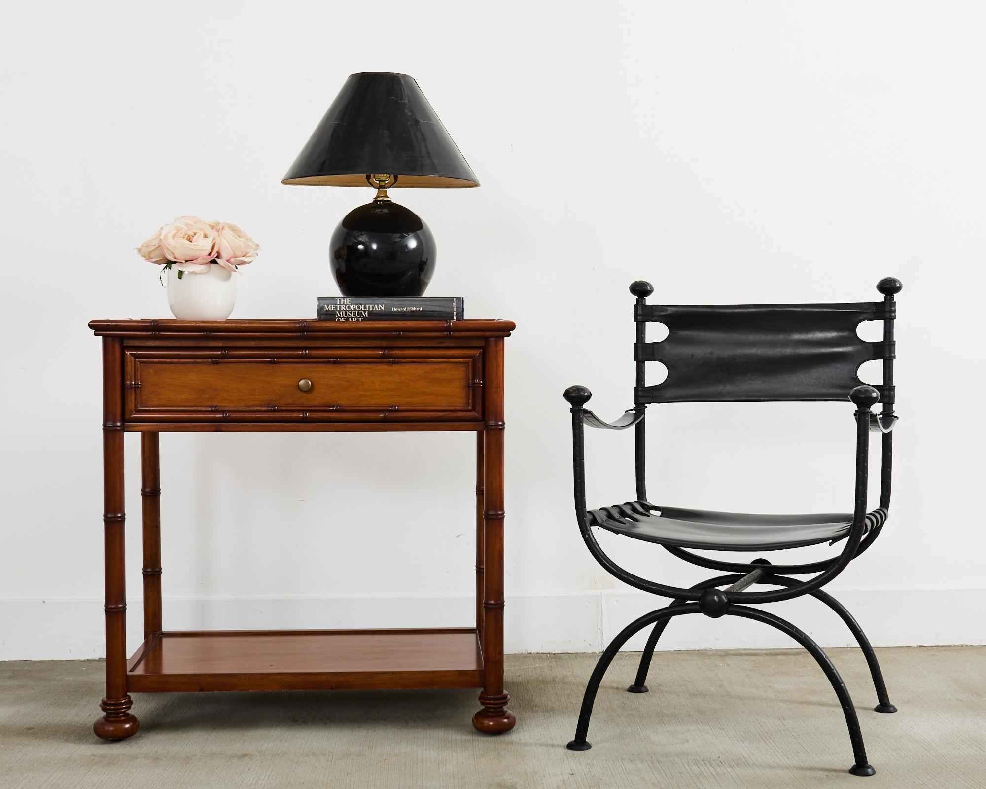 Gorgeous pair of faux bamboo carved hardwood nightstands or end tables. The tables feature a two-tier design made in the English aesthetic movement style. Each stand is fronted by a large storage drawer with a patinated brass pull. The top has a