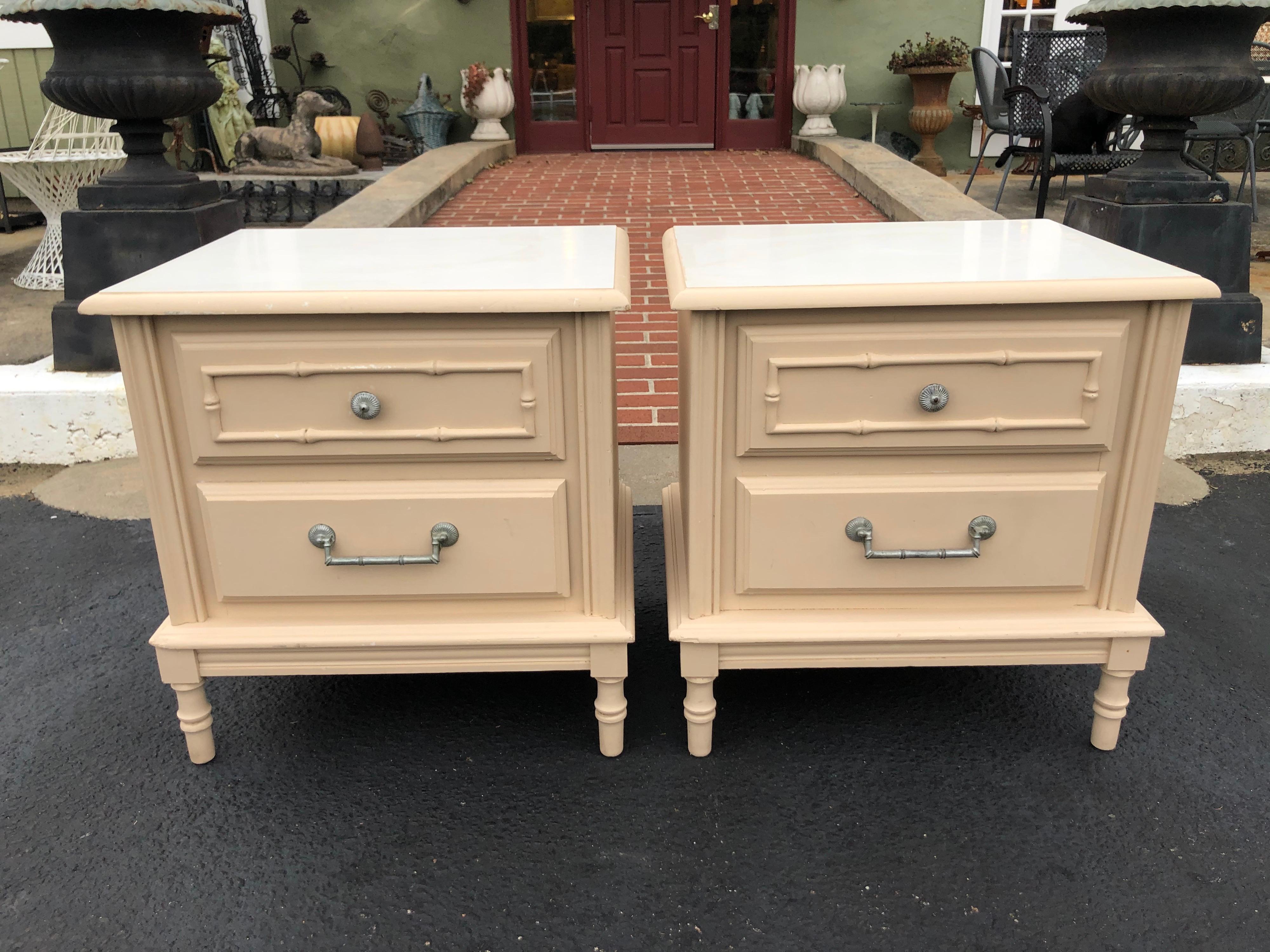 Pair of faux bamboo nightstands in the style of Henry Link. Classic lines and design. We think these would be amazing in a gloss gray. White laminate top with decorative silver toned hardware. Currently painted in a soft matte beige pink.


   