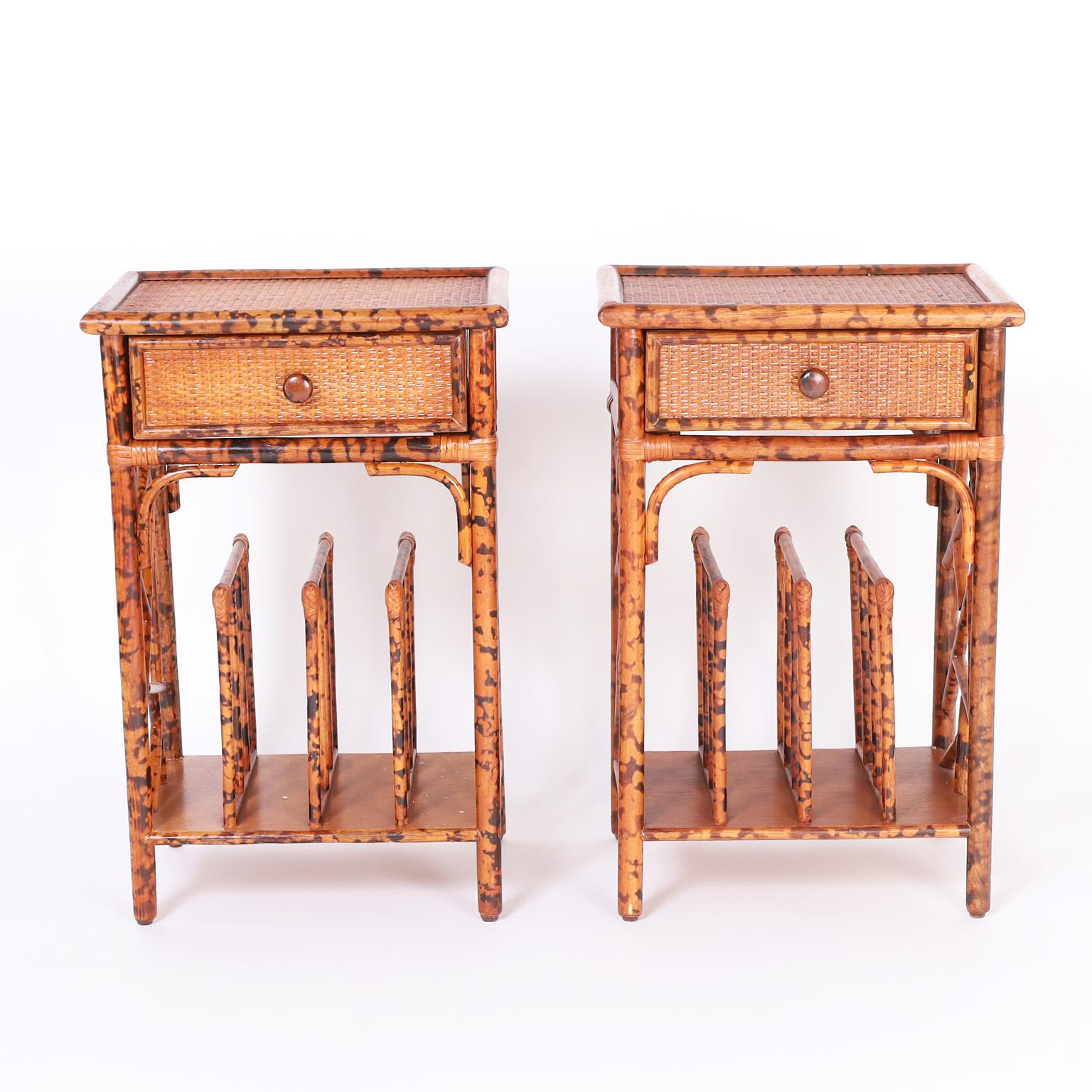 Unusual pair of British colonial style stands featuring faux bamboo frames with a faux tortoise finish, grasscloth panels, one drawer that swings both ways, Chinese chippendale sides and bases with magazine racks.