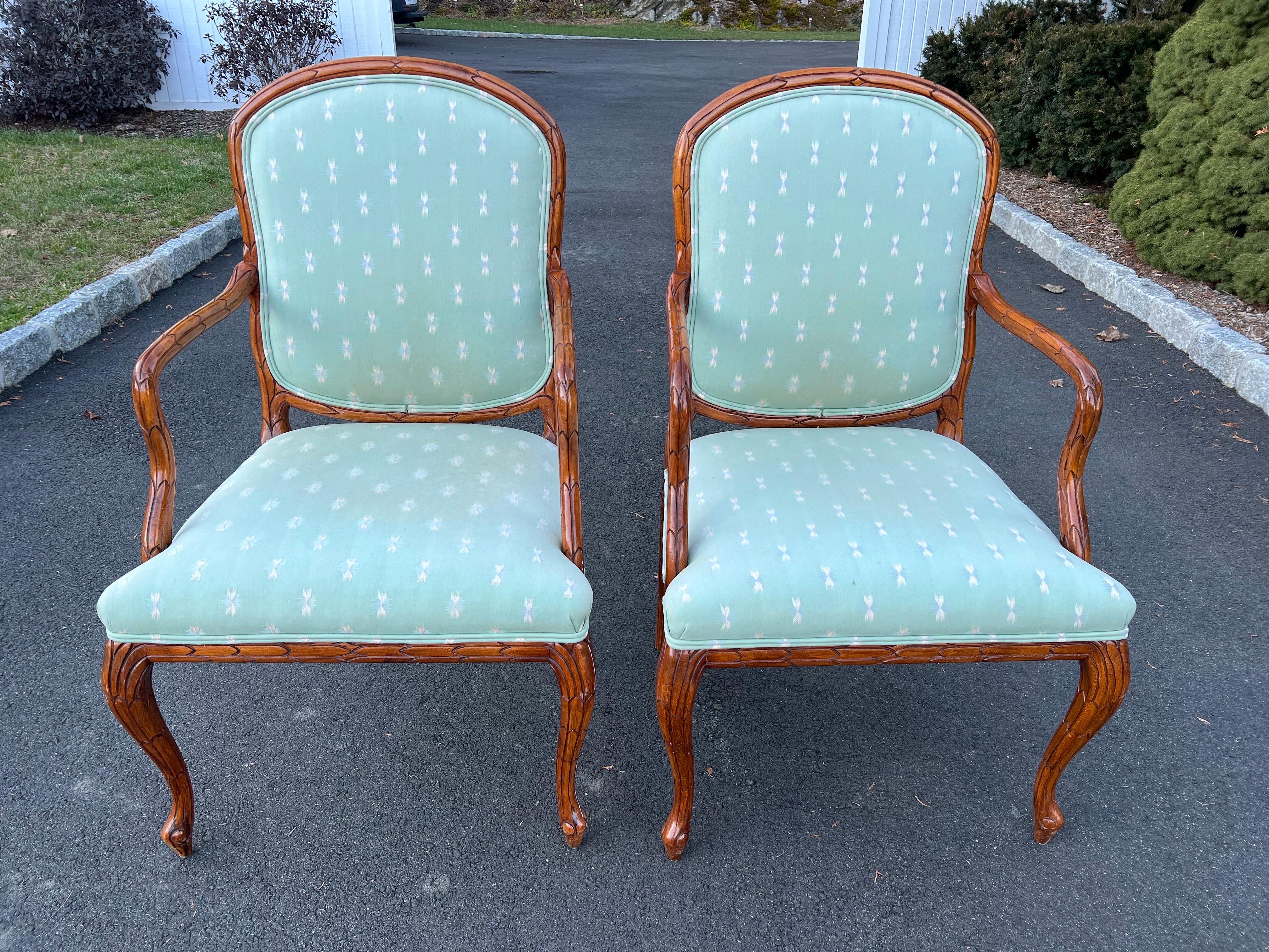 Pair of Faux Bois Bergères in the style of Serge Roche. Classic pair of arm chairs for a living room or bedroom. Solid wooden construction. Elaborately carved in a Faux Bois style. Light sage green upholstery with accents of pink and white. The arm