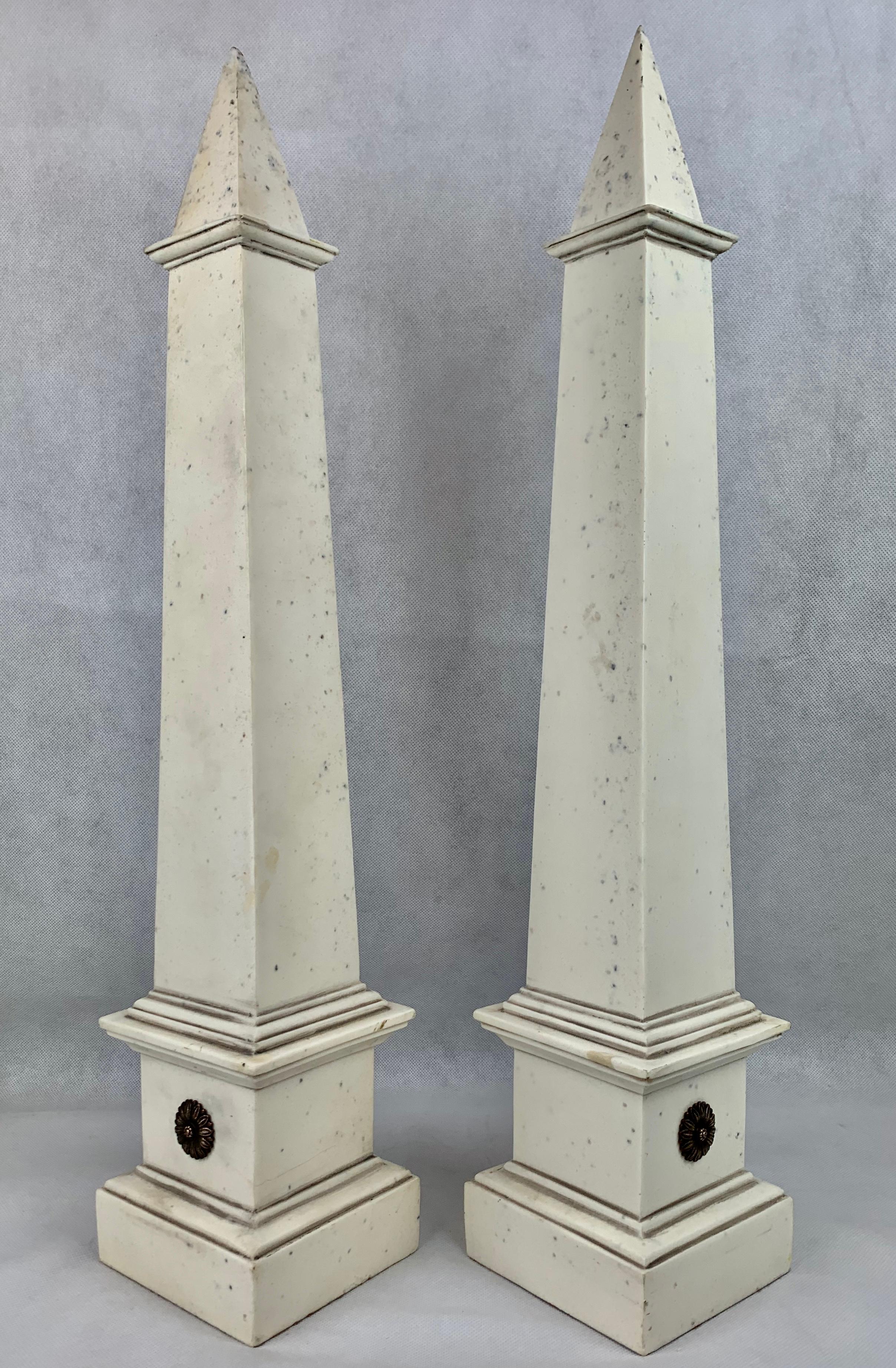 Zwei atemberaubend hohe neoklassizistische Obelisken aus Faux-Ivoire. Bearbeitetes Design, wobei jeder Obelisk ein einzelnes Paar vergoldeter Margeritenblüten zur Verzierung aufweist.
Die Spitze jedes Obelisken ist ein wenig rau.

Height-23.5