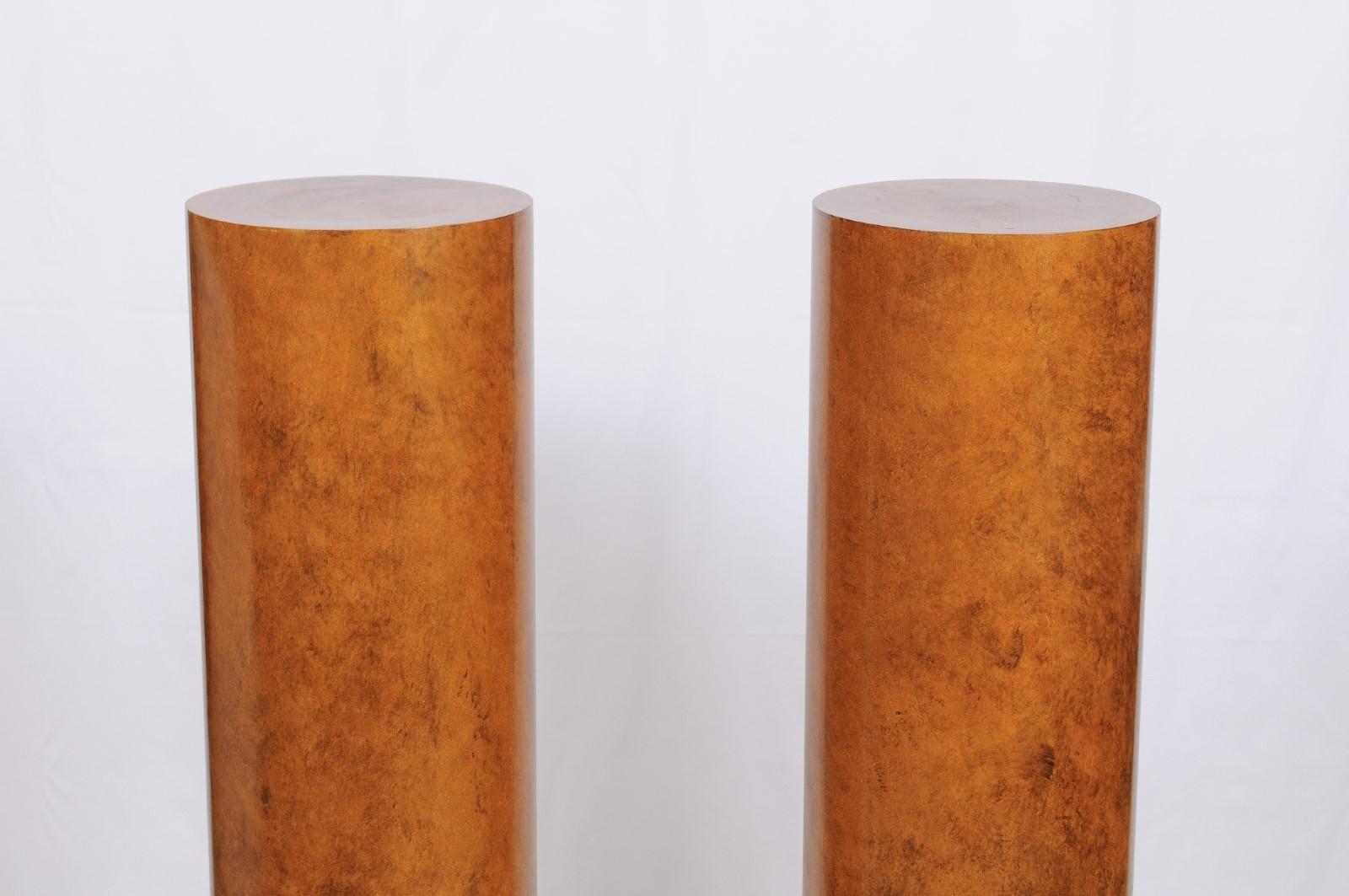 Pair of faux painted column pedestals from the collection of Judith & Gerson Leiber. The finish is painted in a faux bois style to replicate bird's-eye maple with Classic black bases, and all set within a clean Art Deco style.