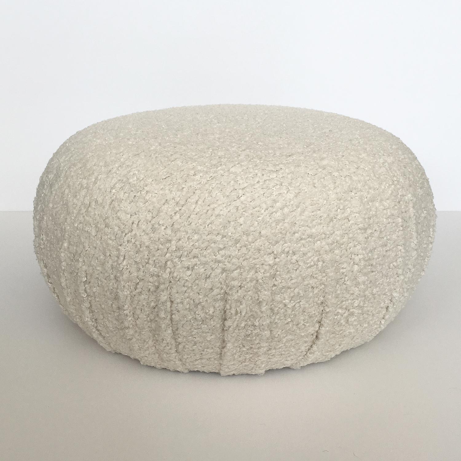 Pair of fully upholstered round souffle pouf ottomans. Newly constructed and upholstered in an off-white natural faux shearling / sheepskin with soft, curly, nubby texture. Excellent option for additional seating or foot stools. Fabric swatches are