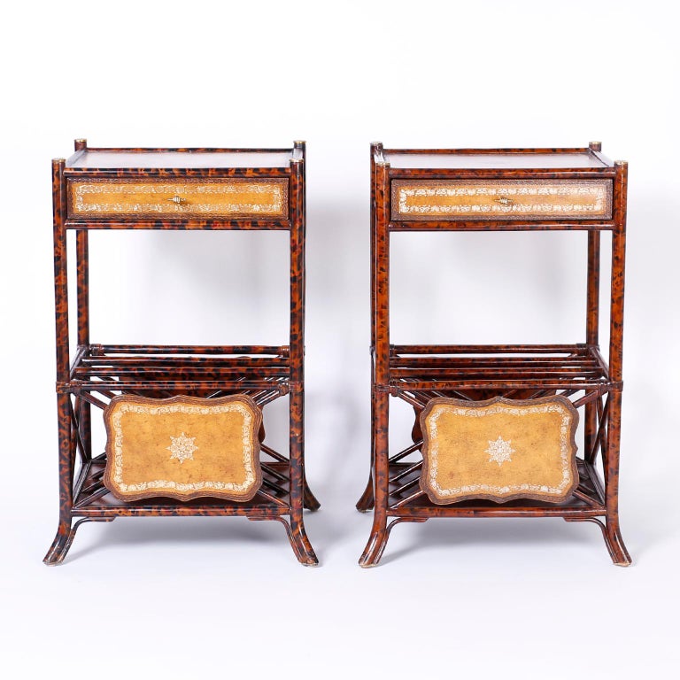 British Colonial style end tables or stands with a faux tortoise finish over a turned wood faux bamboo frame. Featuring tooled brown leather panels, distinctive brass hardware, magazine racks and splayed legs. Signed Maitland-Smith on the bottoms.