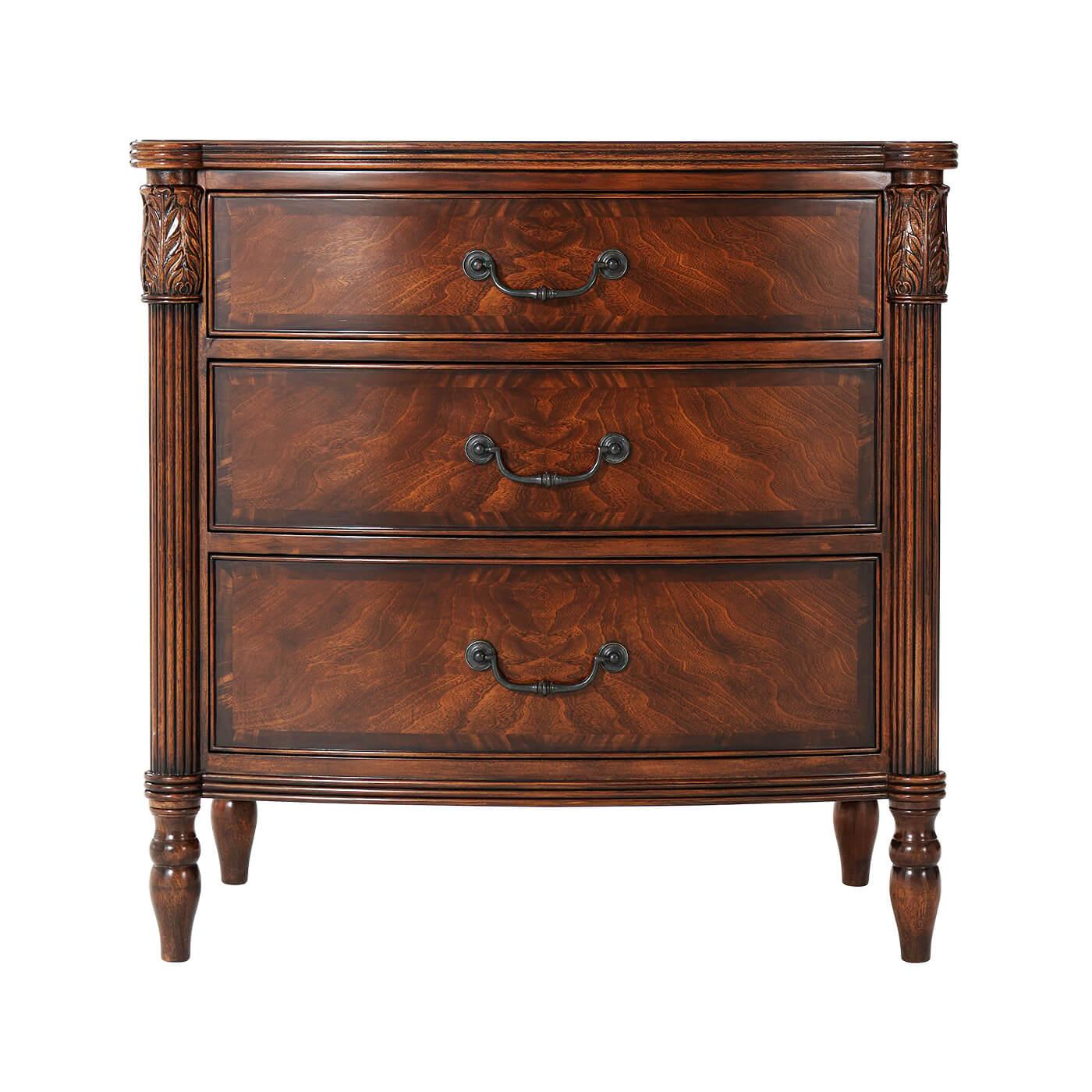 A mahogany and figured mahogany nightstand, the reeded edge bowfront top with protruding corners with leaf carved and reeded uprights, with three graduated drawers with verdigris brass handles, raised on turned legs. Inspired by a Federal Period