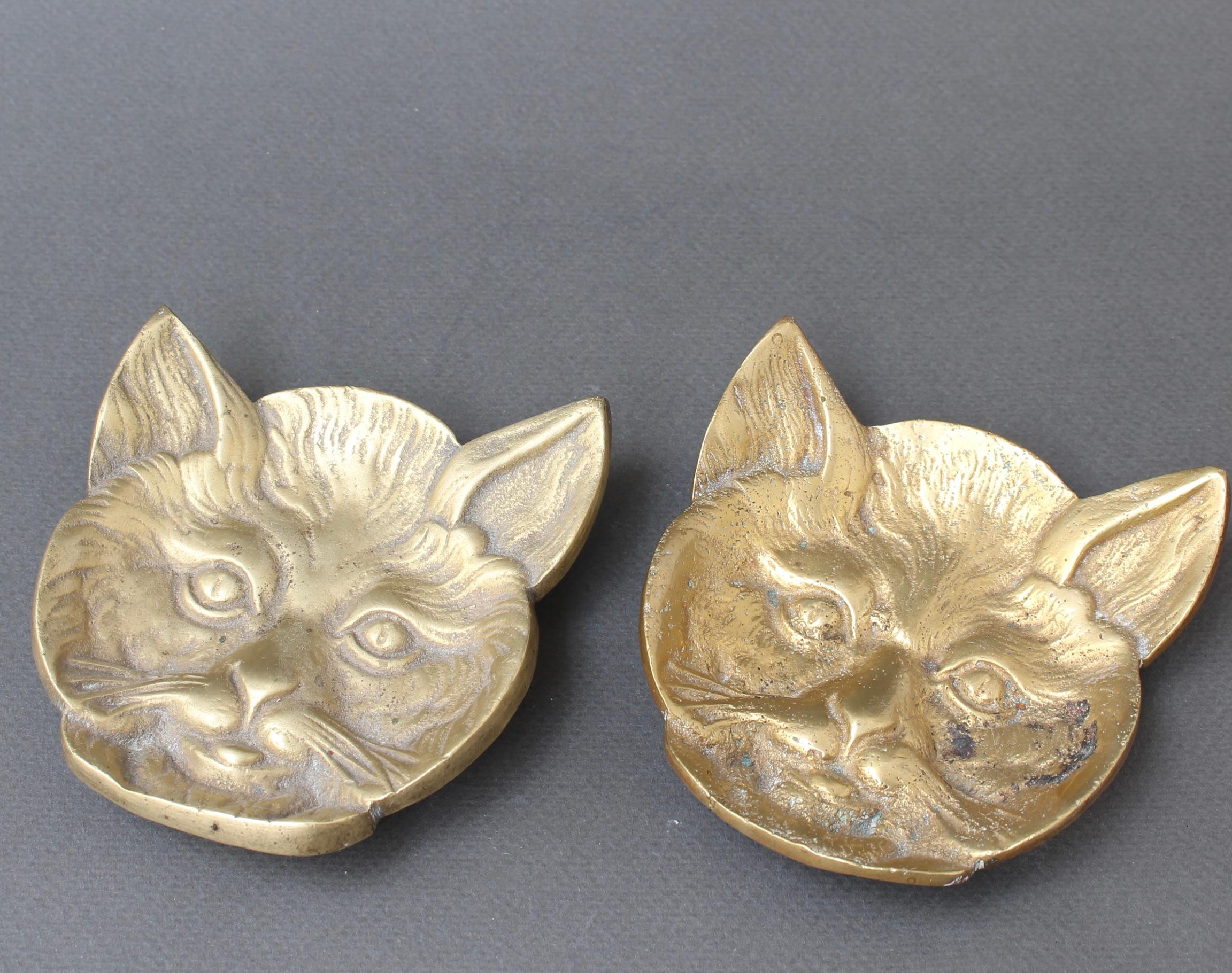Coppia di vides-poches feline in ottone (XX secolo). Piatti di charme, piccoli e pesanti, che possono essere utili o decorativi. Uno dei gatti ha una patina lucida, l'altro è opaco. La patina, come il passare del tempo, ha conferito un certo