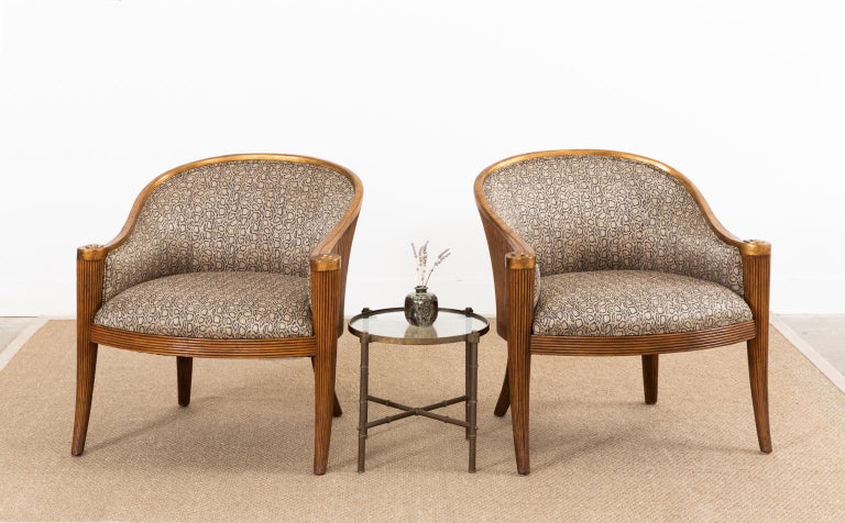 Amazing pair of barrel formed armchairs or lounge chairs made by Ferguson-Copeland. The chairs feature a gracefully curved frame with a dramatic silhouette. The frames have a split rattan reeded veneer finish with a gilt wood horseshoe shaped crest.