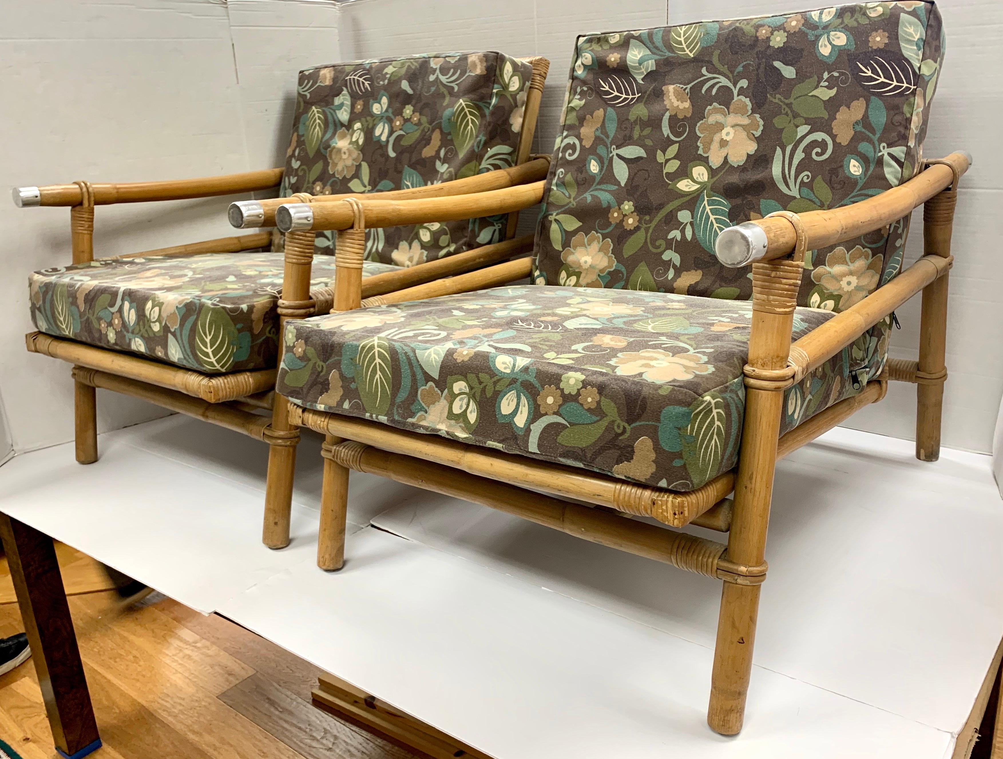 An coveted pair of vintage Campaign style lounge chairs made by Ficks Reed and designed by John Wisner, circa 1954. Stout rattan and bamboo frame with a beautiful raffia seat back. Handsome solid metal accents mark the arms. Fabulous design, quality