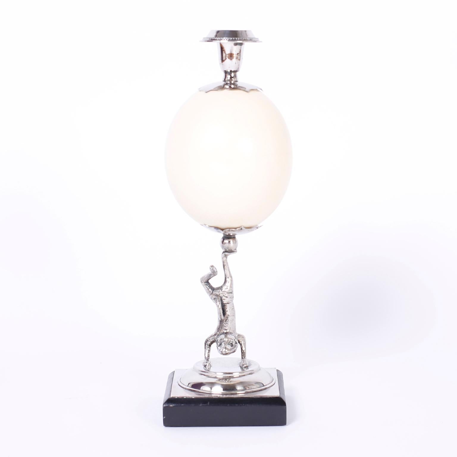Whimsical yet refined pair of candlesticks with silvered metal acrobatic lizards holding ostrich eggs with candle holders on a classic base stamped Redmile London.