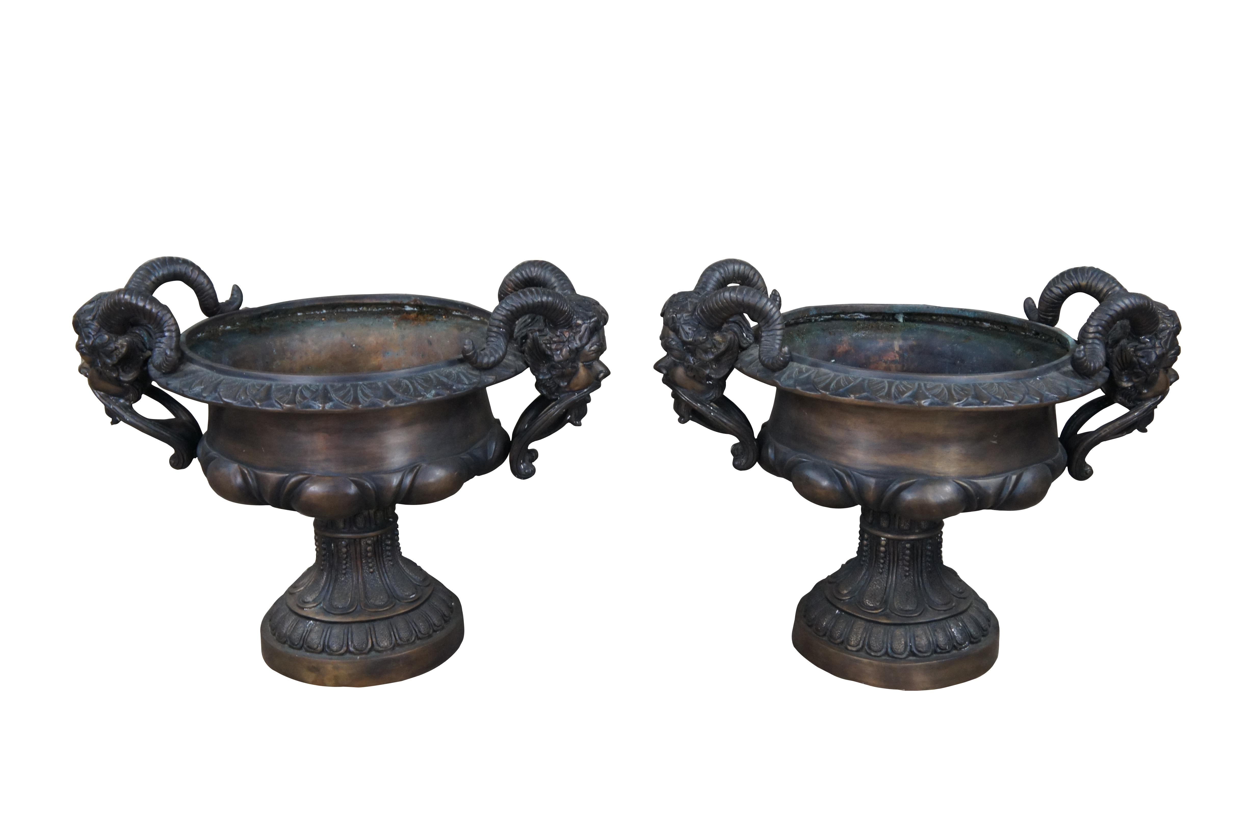 Exceptional set of footed bronze tazza urns. Features traditional Grecian form with gadrooned body and flared mouth with leaf trim. The urn is flanked on each side with magnificent figural Bacchus handles. He is poised with an open mouth, long