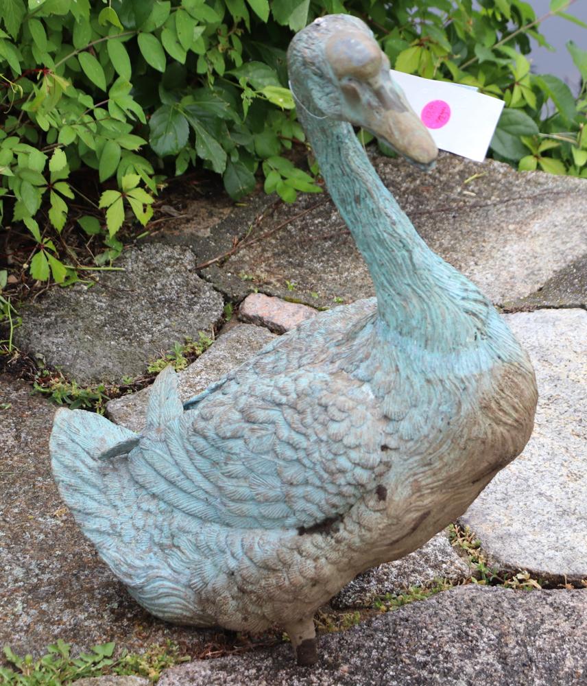 Pair of decorative cast iron figural garden geese. Lovely green/blue patina. Perfect and playful to add a bit of humor and charm to the garden.  One is seated without legs, and two spikes sit on the grass.  The other is in full flight with wings