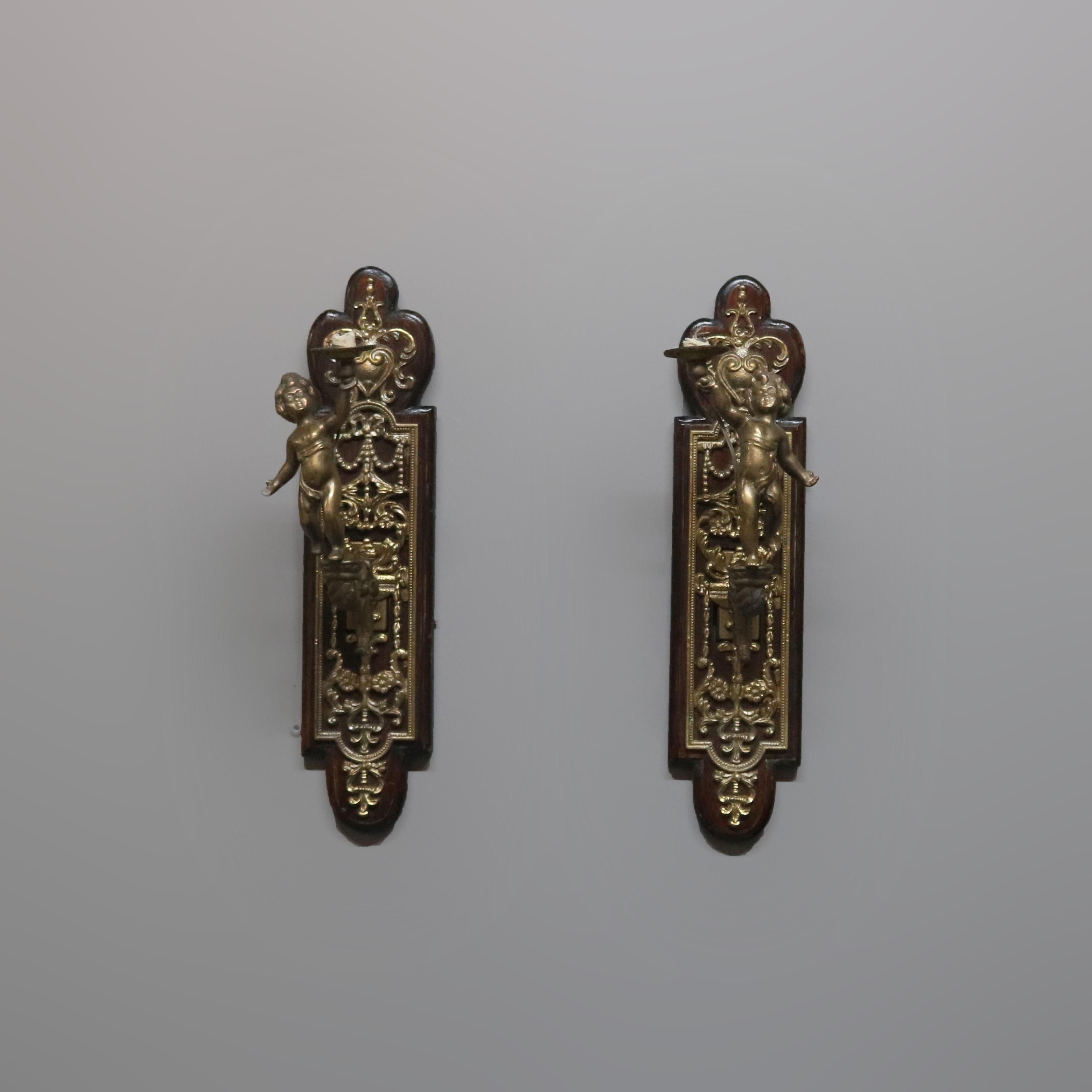 An antique pair of figural wall sconces offer shaped mahogany wall plates with cast and gilt metal cherub form arms terminating in candle lights, electrified, circa1900

 Measures: 6.25