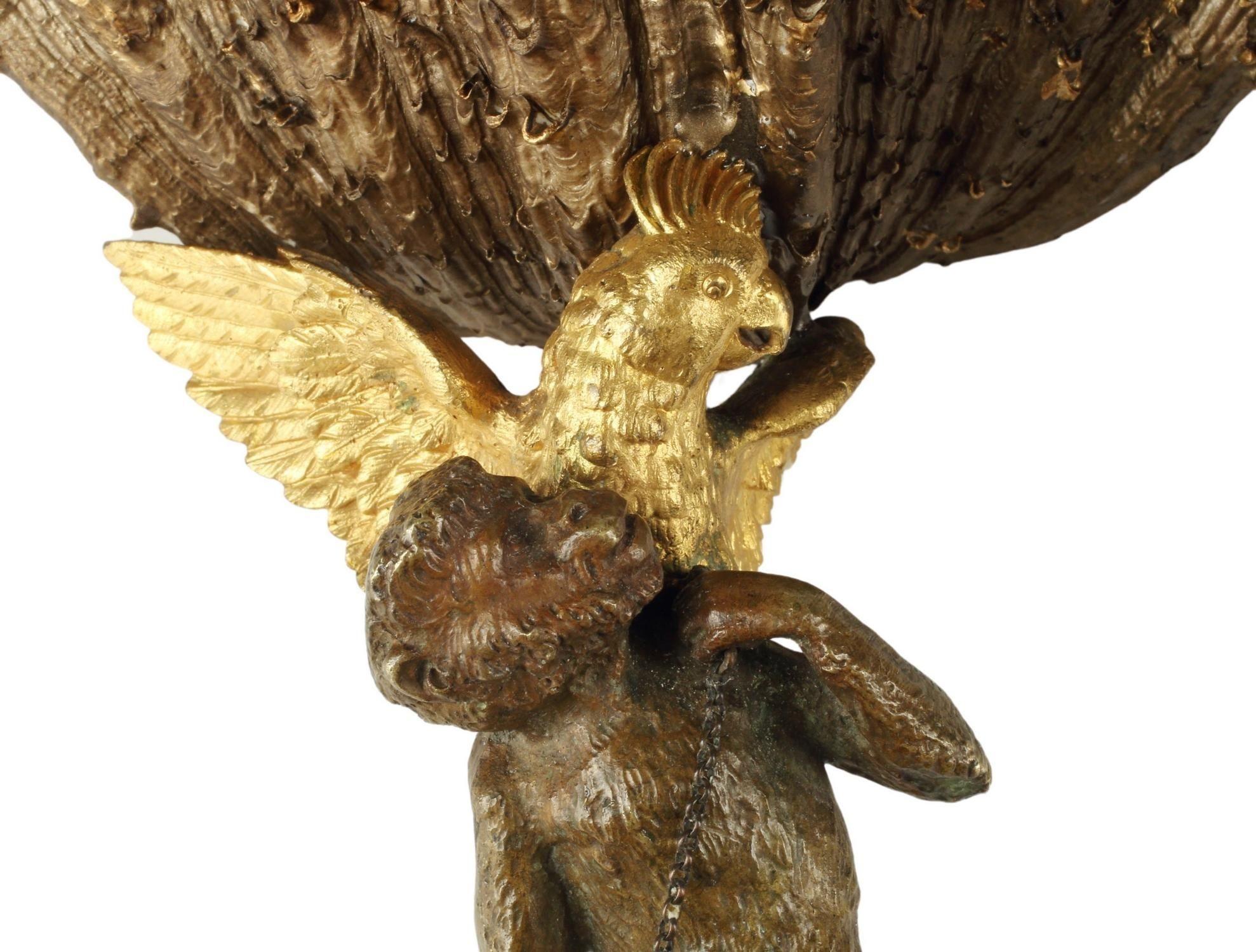 Pair of patinated and gilt bronze garnitures, made in France during the Late 19th Century. Each piece portrays a monkey standing on a Rocaille-style base, accompanied by an eagle-like bird perched on his back, supporting a shell with its