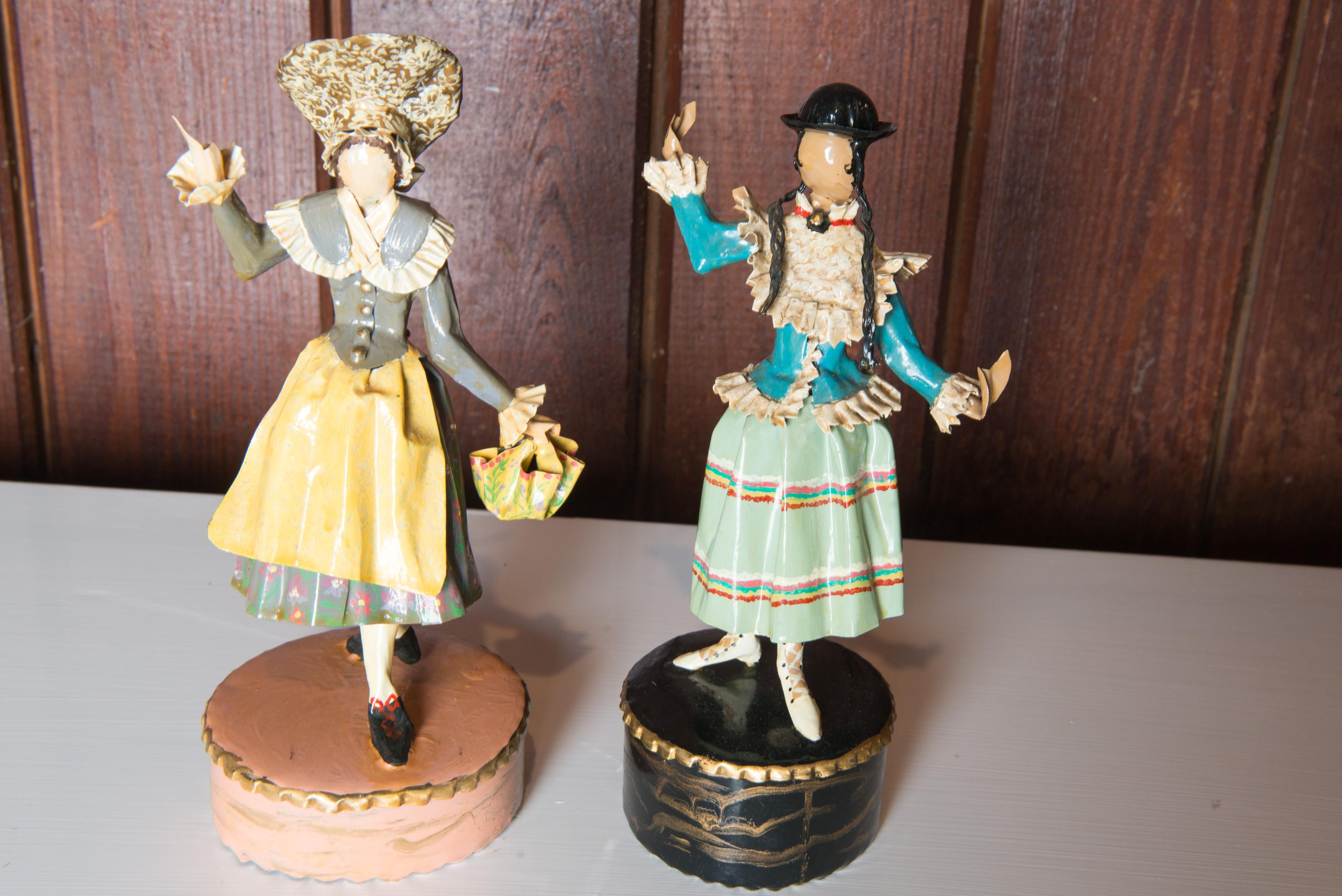 Lee Menichetti, (1931-1997), New York & Palm Beach, well known mid-century artist known for his theatre related art. These sculptures are made of hand bent and hand painted sheet brass. One figure in a dirndl skirt and a bowler hat. The other in a