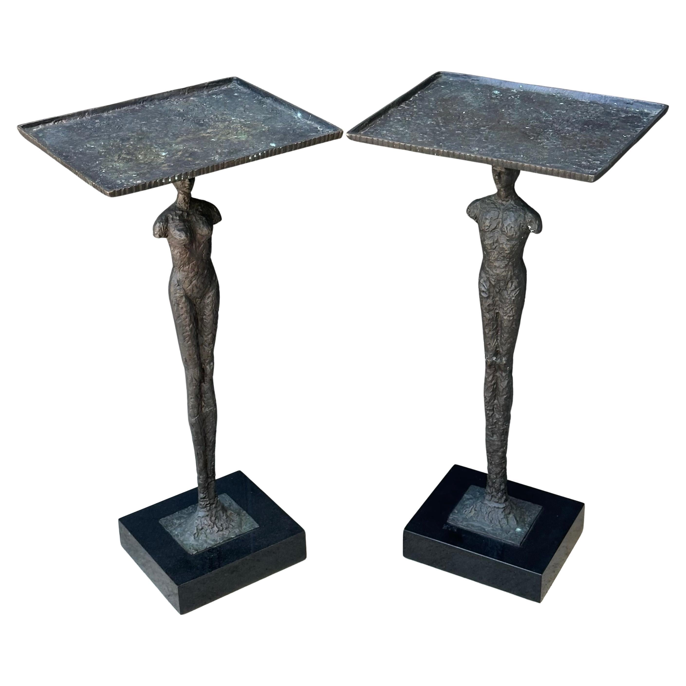 Pair of figurative bronze man and woman side tables in the style of Alberto Giacometti, circa 2000s. The tables sit on solid block of black marble that measures 8.5
