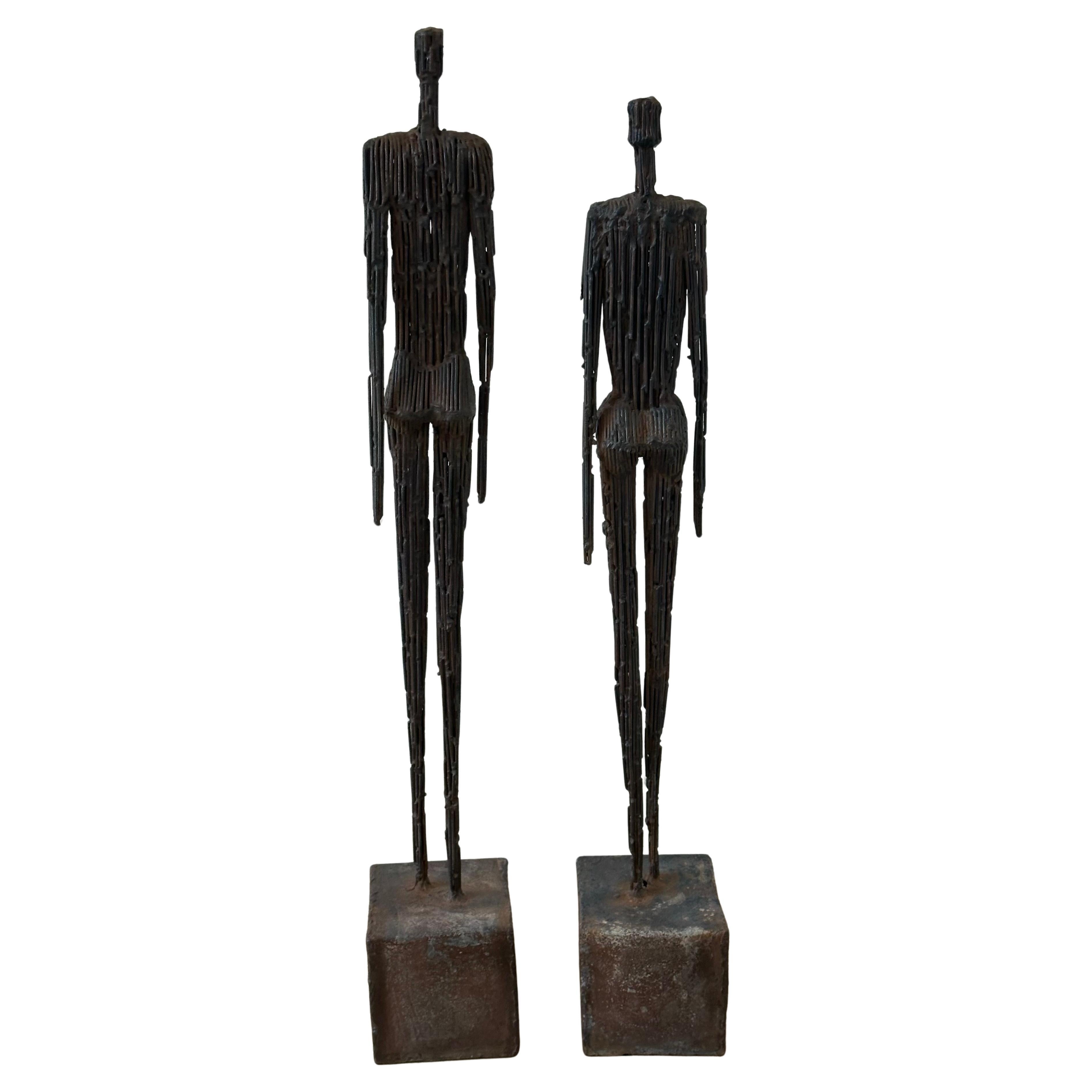 Pareja de esculturas figurativas de hombre y mujer de metal al estilo de Giacometti