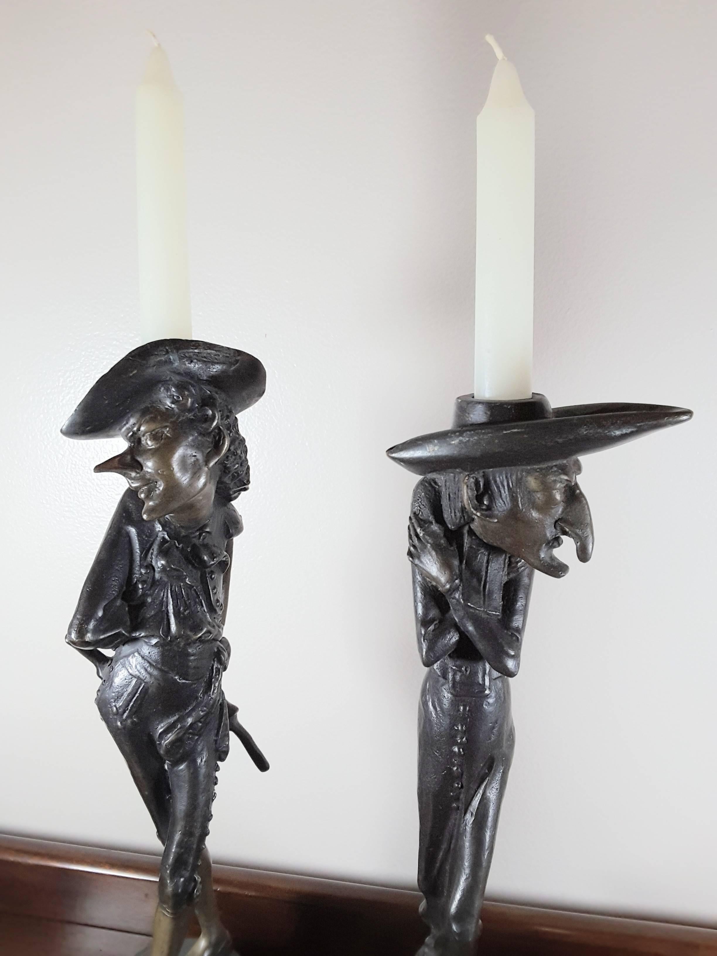A pair of Fin De Siecle French Grotesque candlesticks, very stylized figures with elongated facial features and body styles. Done in a patinated bronze, Signed on the circular plinth bases (please see pic), One figure is in a long robe coat and the