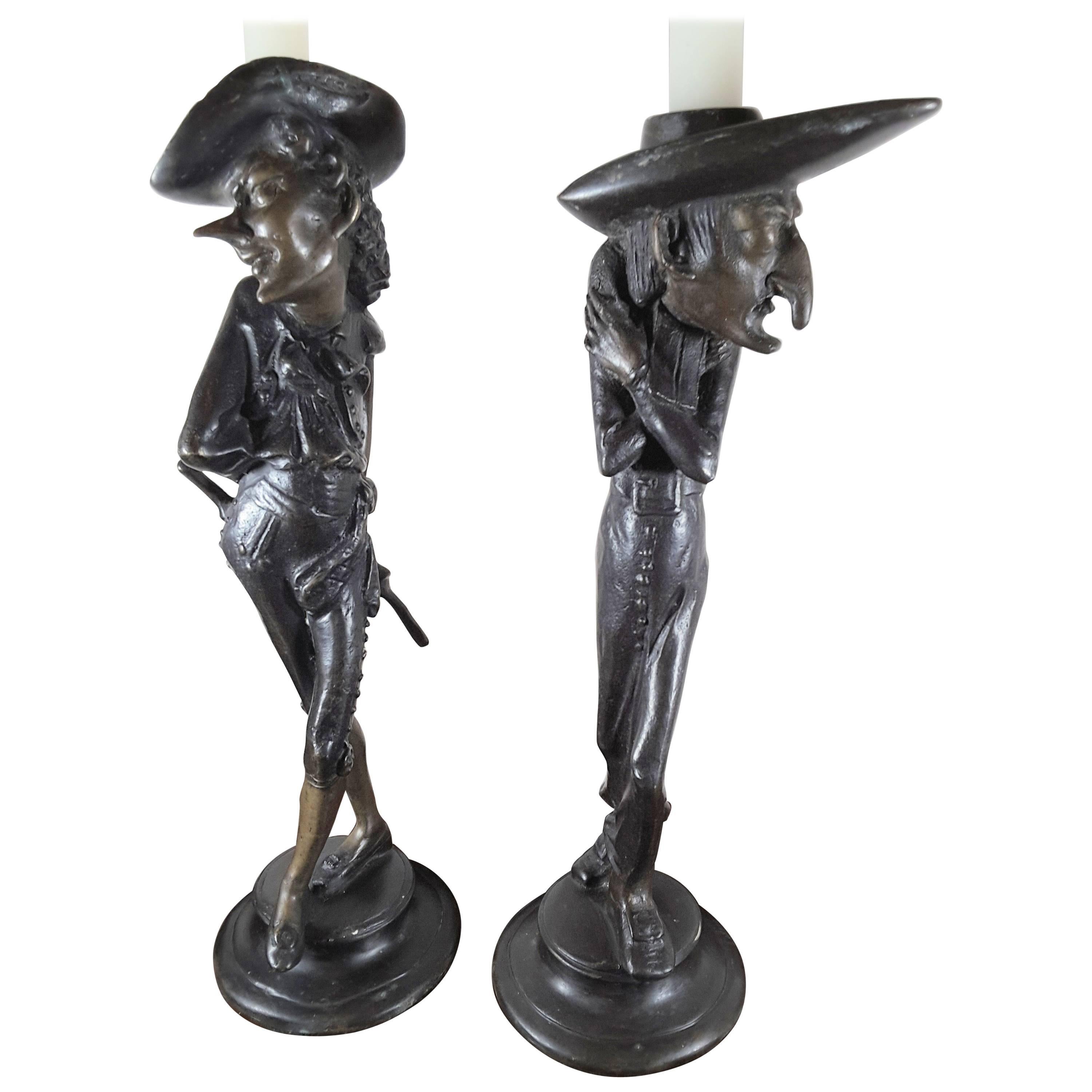A pair of Fin De Siecle French Grotesque candlesticks, very stylized figures with elongated facial features and body styles. Done in a patinated bronze, signed on the circular plinth bases (please see pic), one figure is in a long robe coat and the