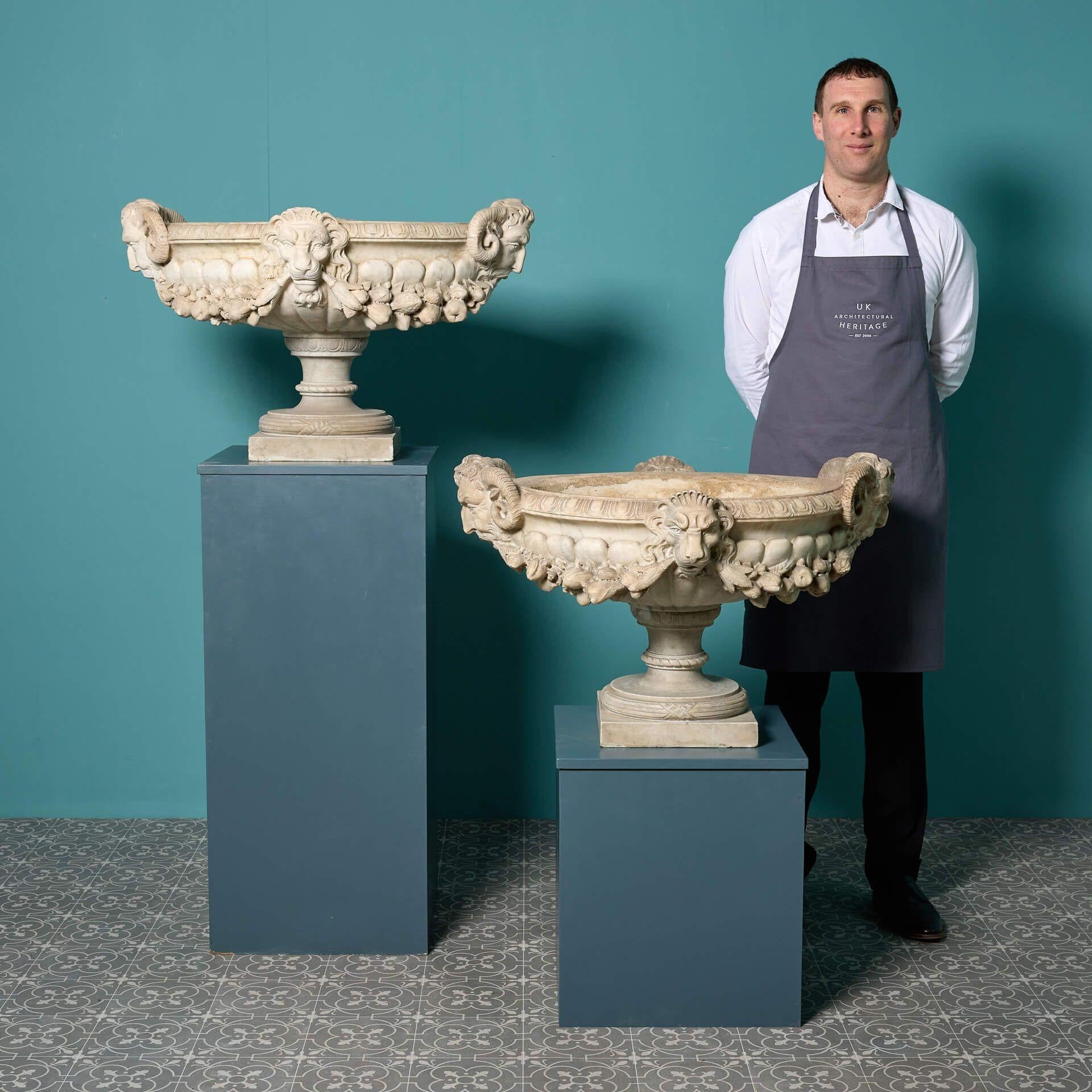 Une grande et impressionnante paire d'urnes tazza en marbre italien vers 1830.

Très ornée, chaque urne en marbre de Carrare fabriquée à la main est de forme ovale avec une bordure à godrons, les extrémités étant sculptées de masques de satyres