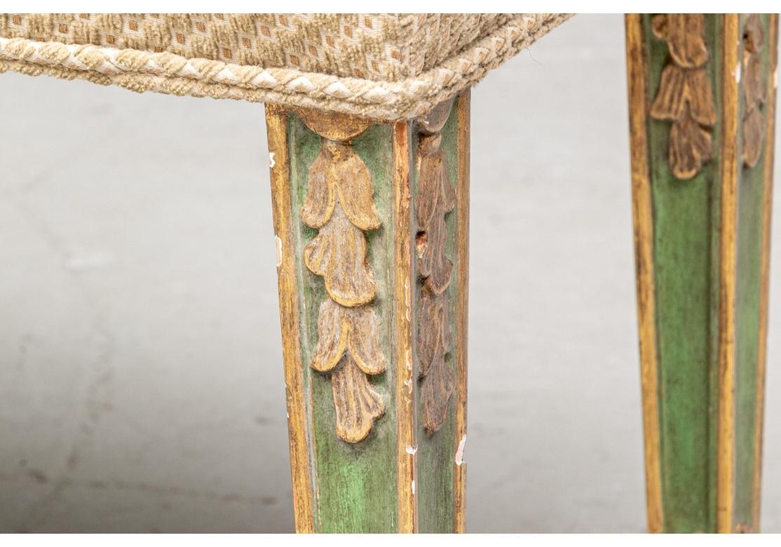 Exceptional pair of fine antique benches in green paint with gilt embellished carved legs. The distressed legs with trailing gilt bell flowers and resting on relief carved feet. The benches are custom upholstered in pale green with brown chenille