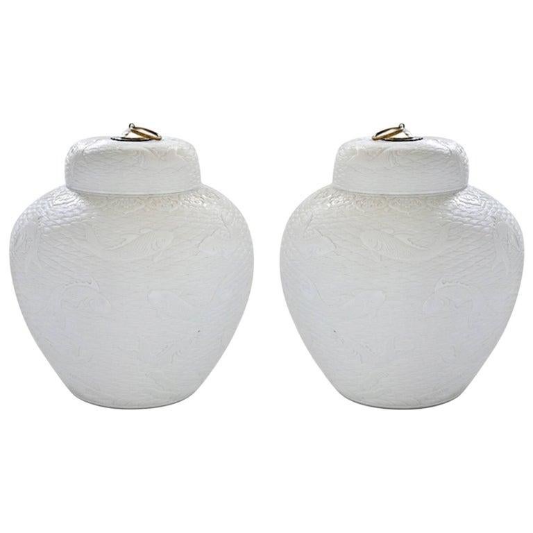 A pair of fine carved white porcelain jars with fish swimming in the stylish wave decoration