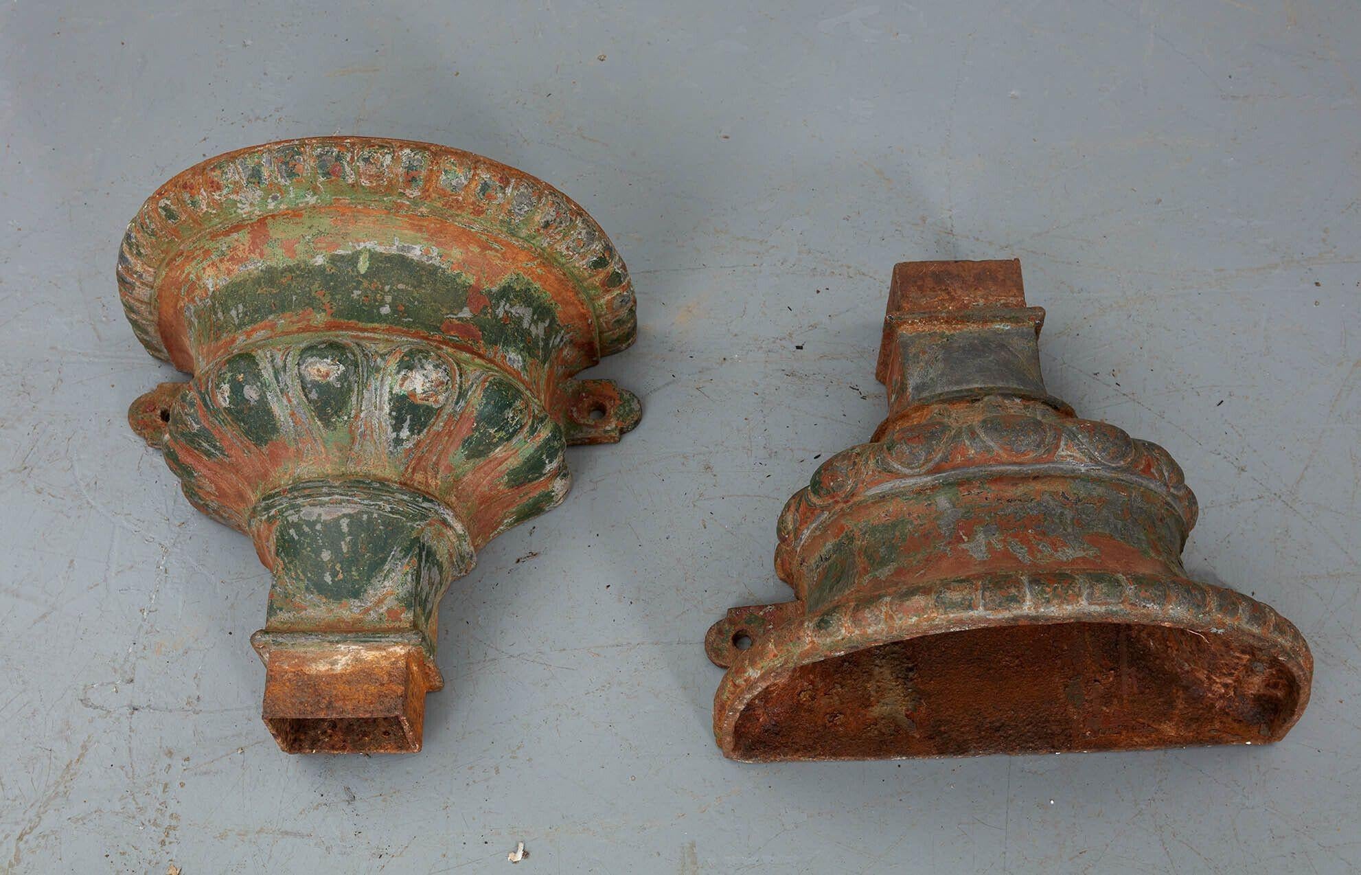 A pair of heavy finely cast iron rain hoppers in the form of classical urns with flared mouths, curved waists and gadrooning to rims and bodies. Attractive weathered surfaces retaining traces of original paint. Now useful as unique wall-mounted