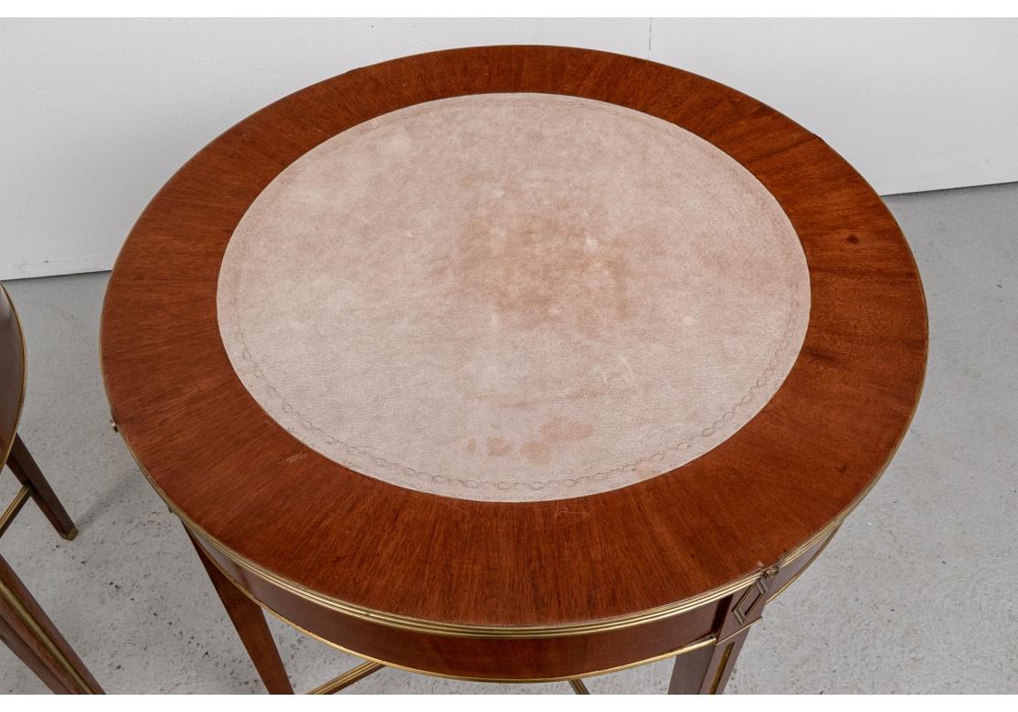Una coppia particolarmente raffinata ed eccezionale di Drum End Table con piano in pelle scamosciata. I piani sono caratterizzati da fasce esterne in mogano e da centri in pelle lavorata in tonalità taupe chiaro. I bordi superiori in ottone a coste
