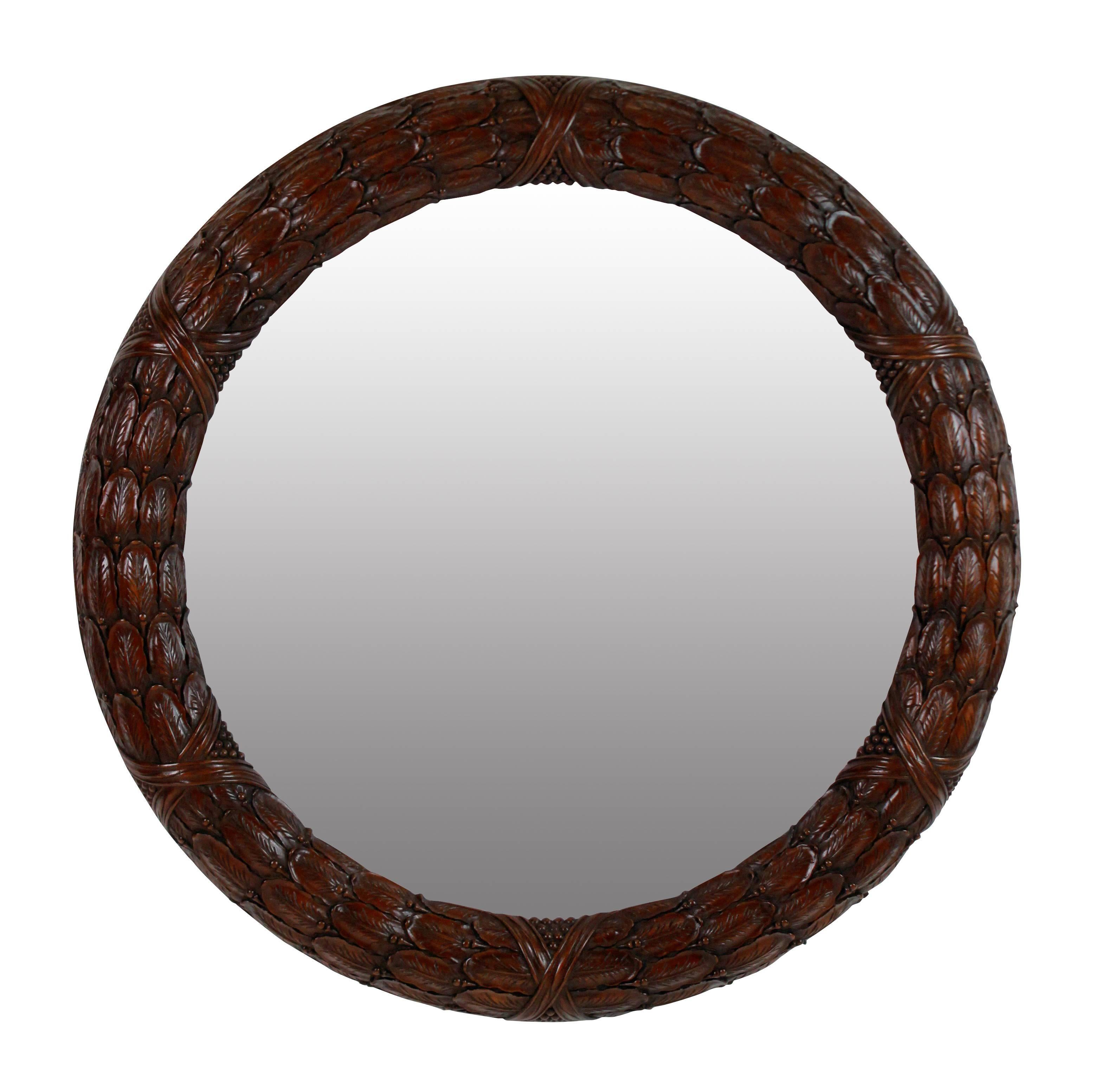 A pair of English finely carved mahogany laurel wreath circular mirrors with distressed mirror plates.
  