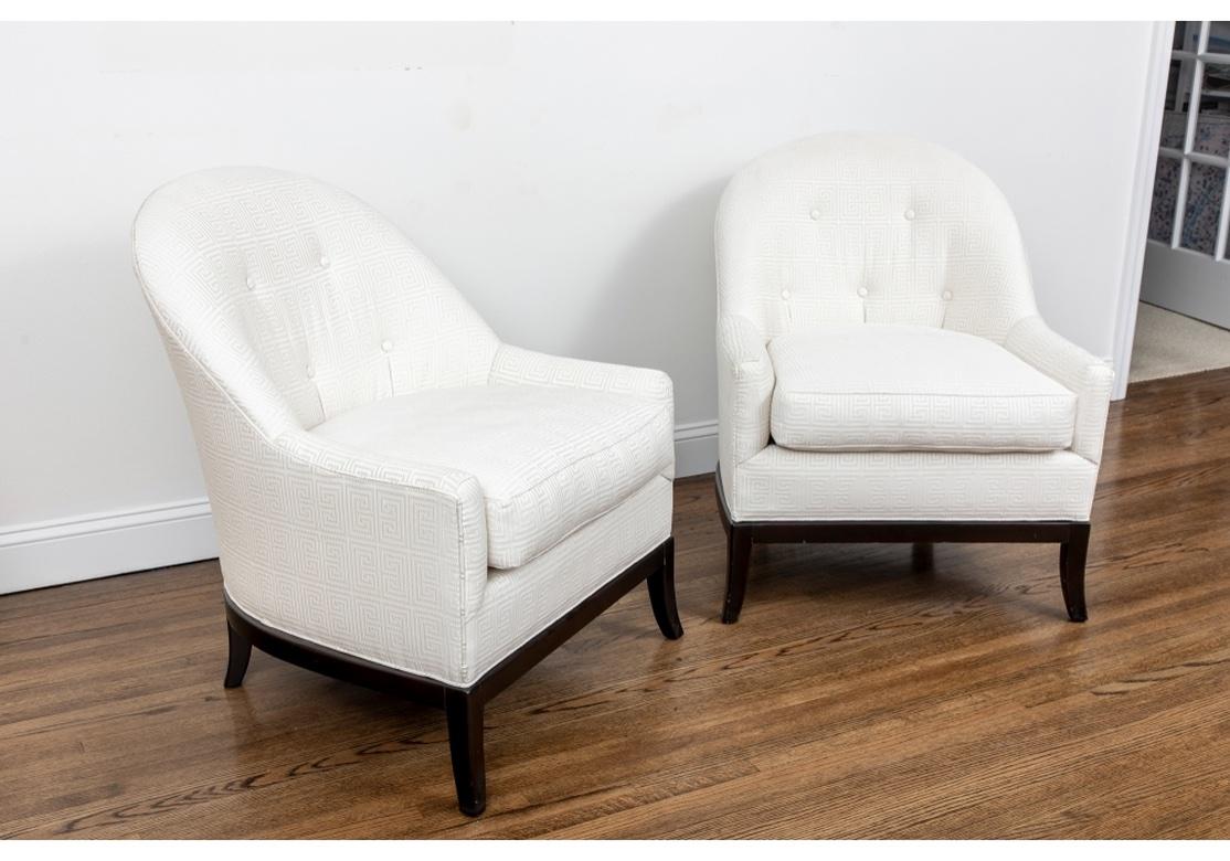 Elegant and well-constructed club chairs with ebonized wood frames, raised on square splayed legs. Upholstered in a white textured fabric in Greek Key pattern with button tufted oval backs. 
Measures: Height. 33 3/4