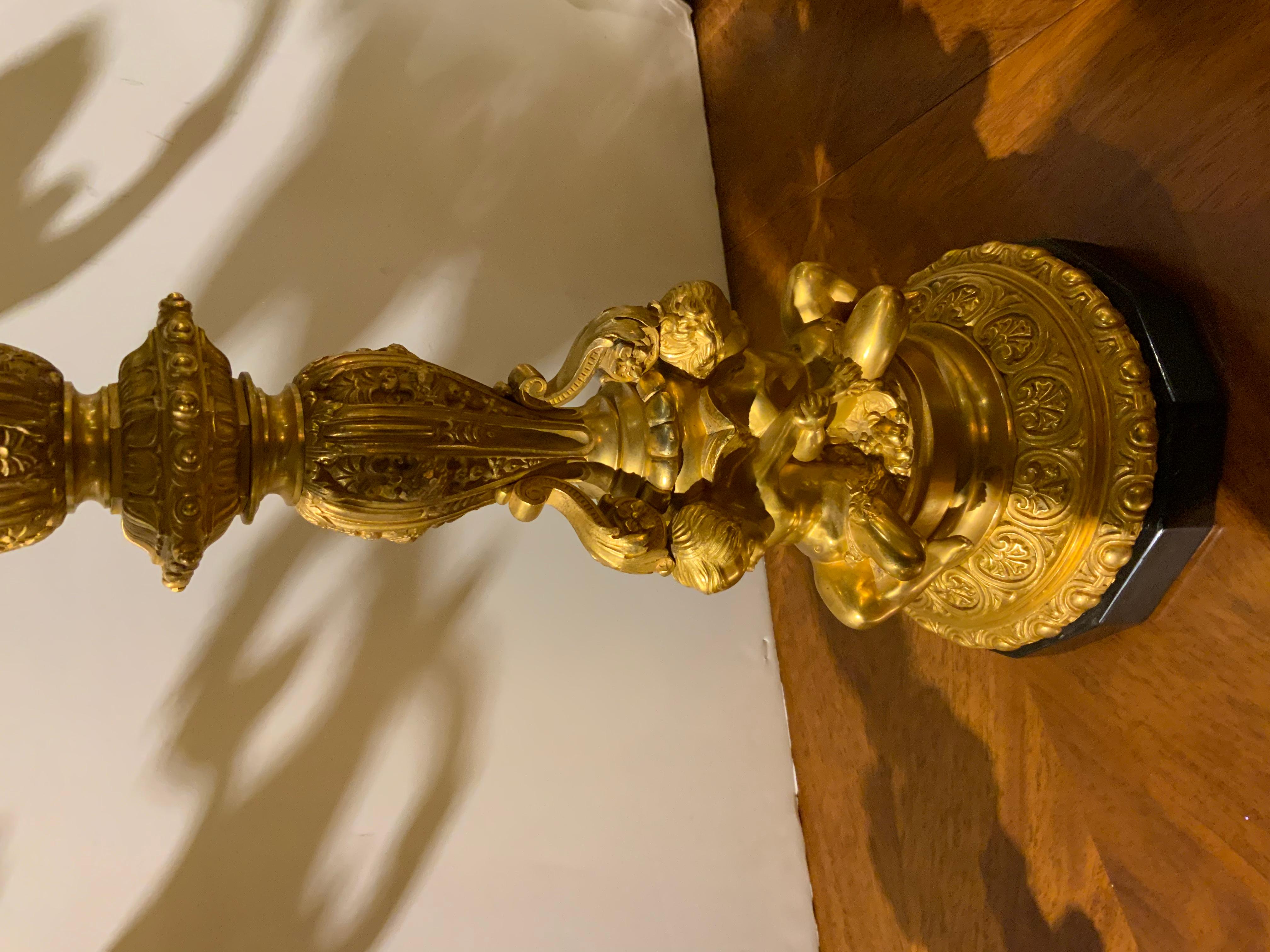 French bronze candleabrum, with foliate scrolling arms, standard with repeated
Pattern in relief, supported by three winged putti, on a twelve sided black slate 
Base.