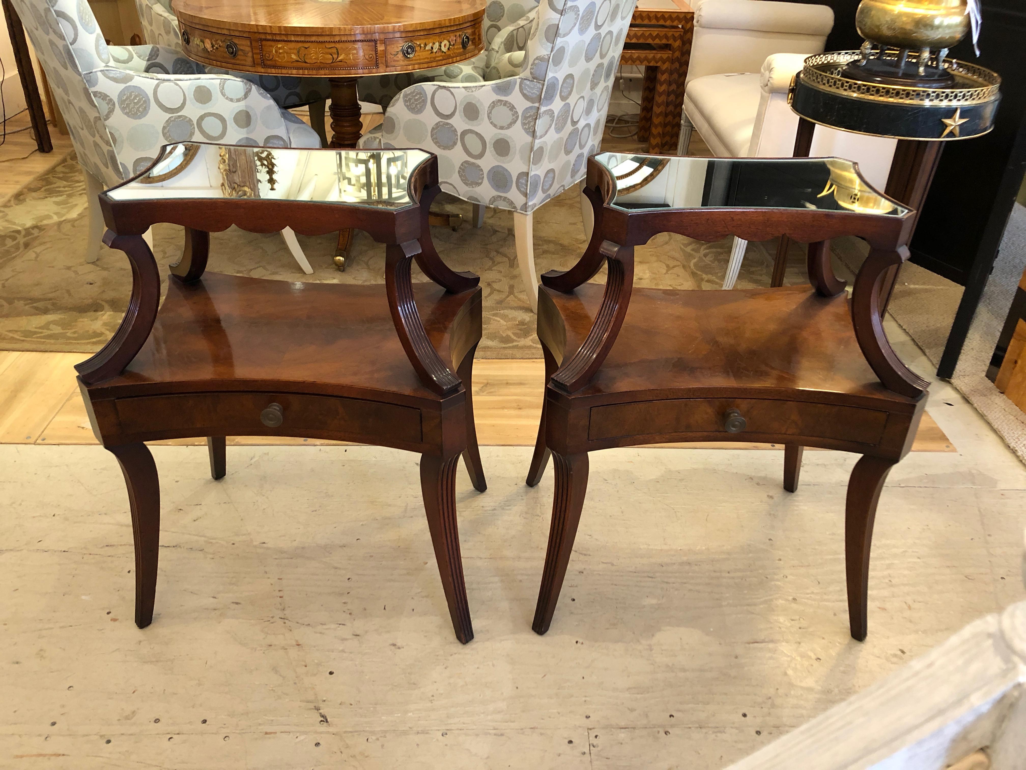 Very fine pair of two-tier crotch mahogany bedside tables or end tables having single drawers in the bottom, lovely splayed legs, scallop decoration around the bottom of the top tier and mirrored top surface.
20 inches H to bottom tier.