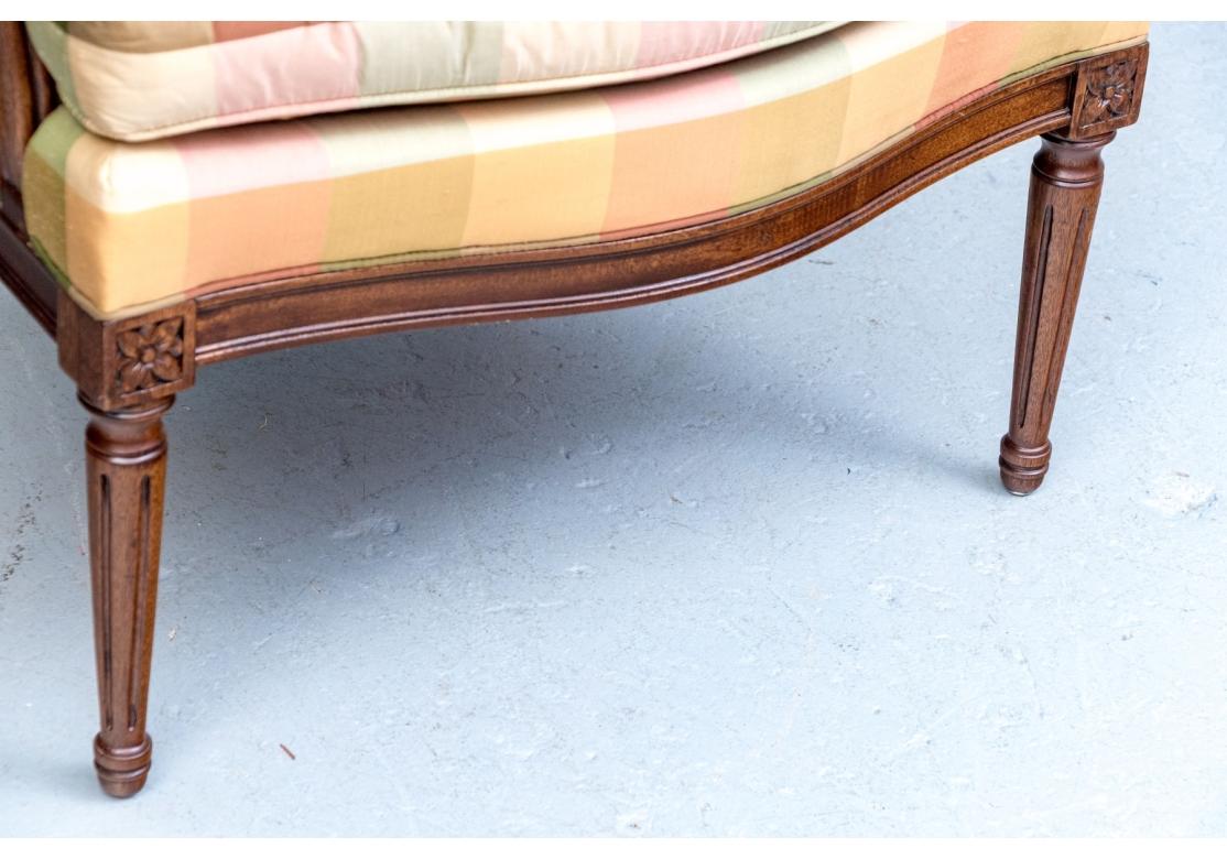 Pair of fine Hickory Chair bergere armchairs covered in multi-color plaid silk fabric. The chairs having covered manchettes, upholstered side panels flanking a complementary striped back with a center stretcher above a covered panel. The armchairs